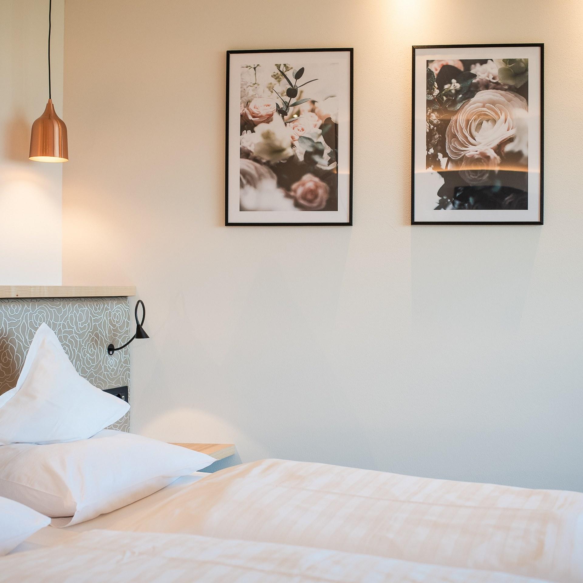 Schlafzimmer im Alpenpalais Kröll mit Doppelbett und Blumenbildern an der Wand
