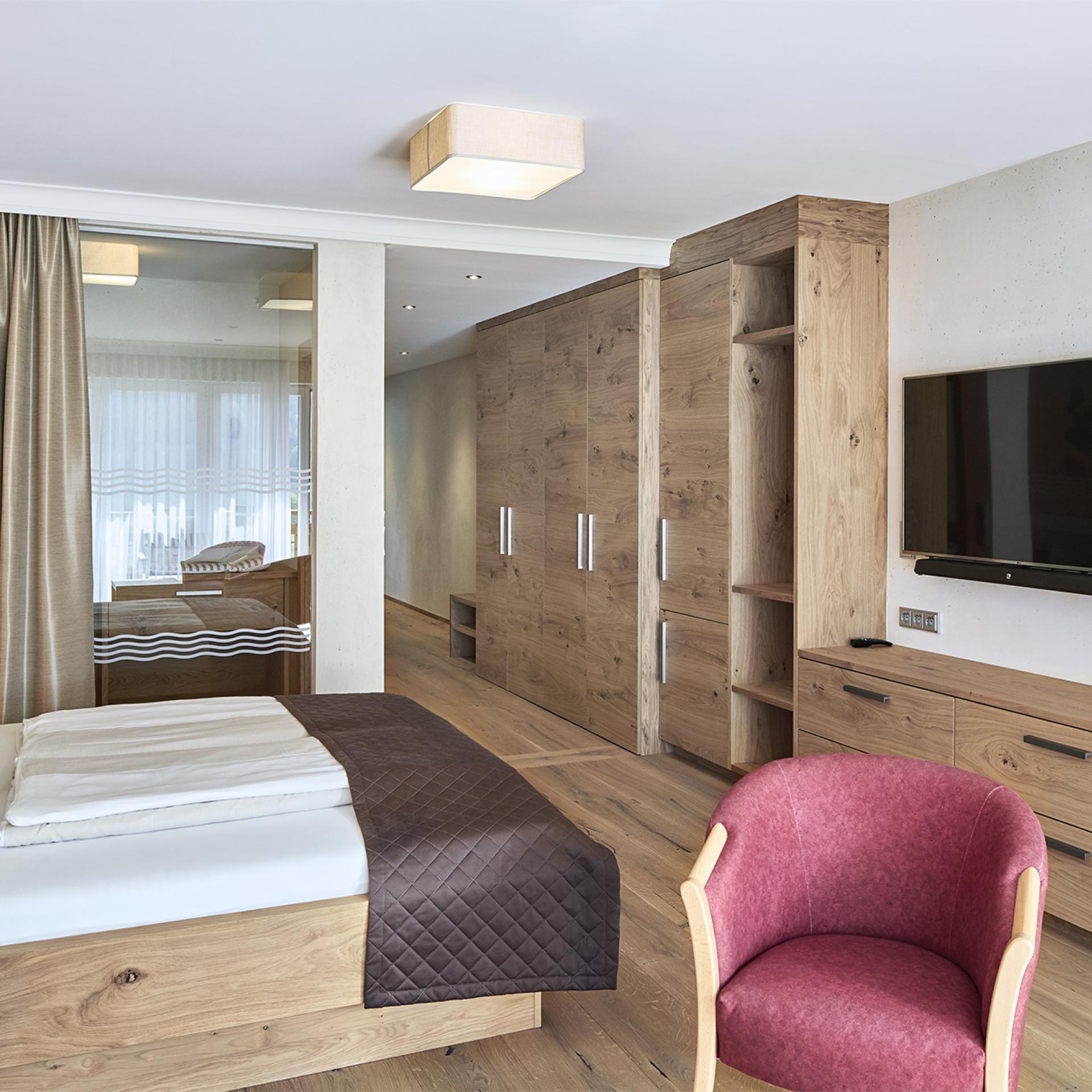 Modern eingerichtetes Zimmer im Familienresort Buchau mit Holzmöbeln und TV