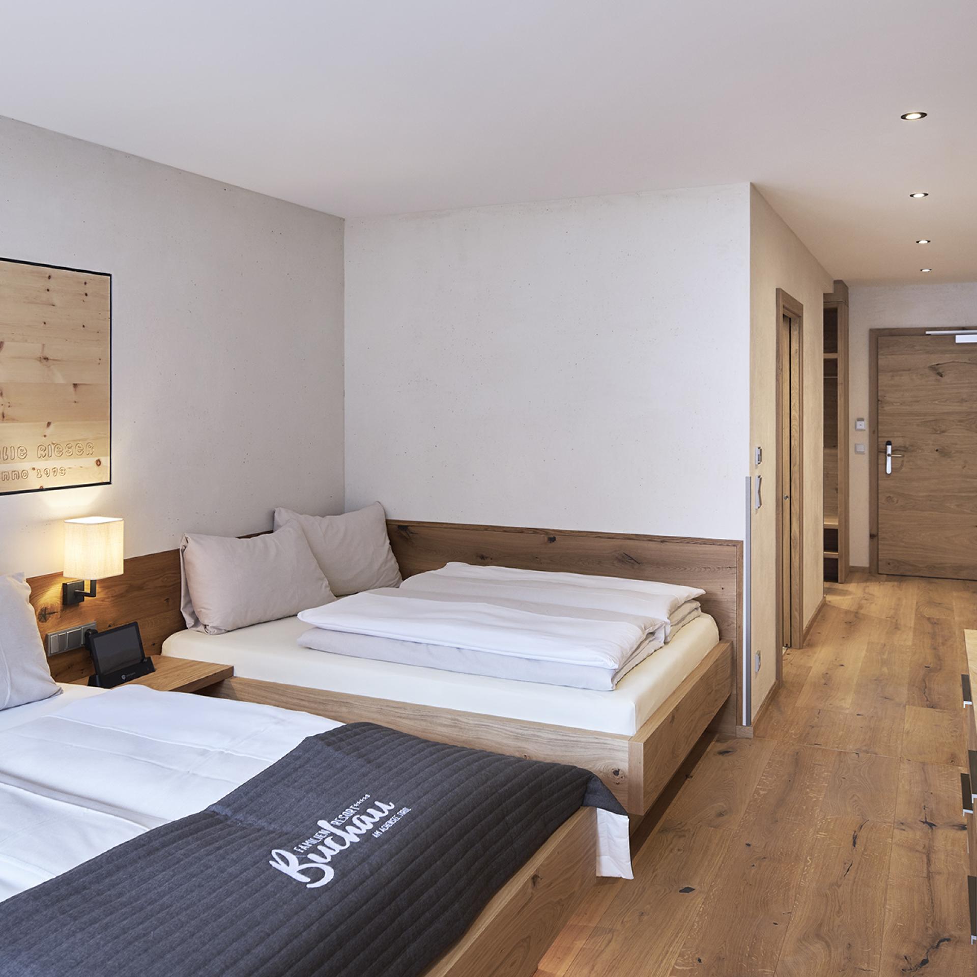 Modernes Familienzimmer im Familienresort Buchau mit Doppelbetten und Holzboden.