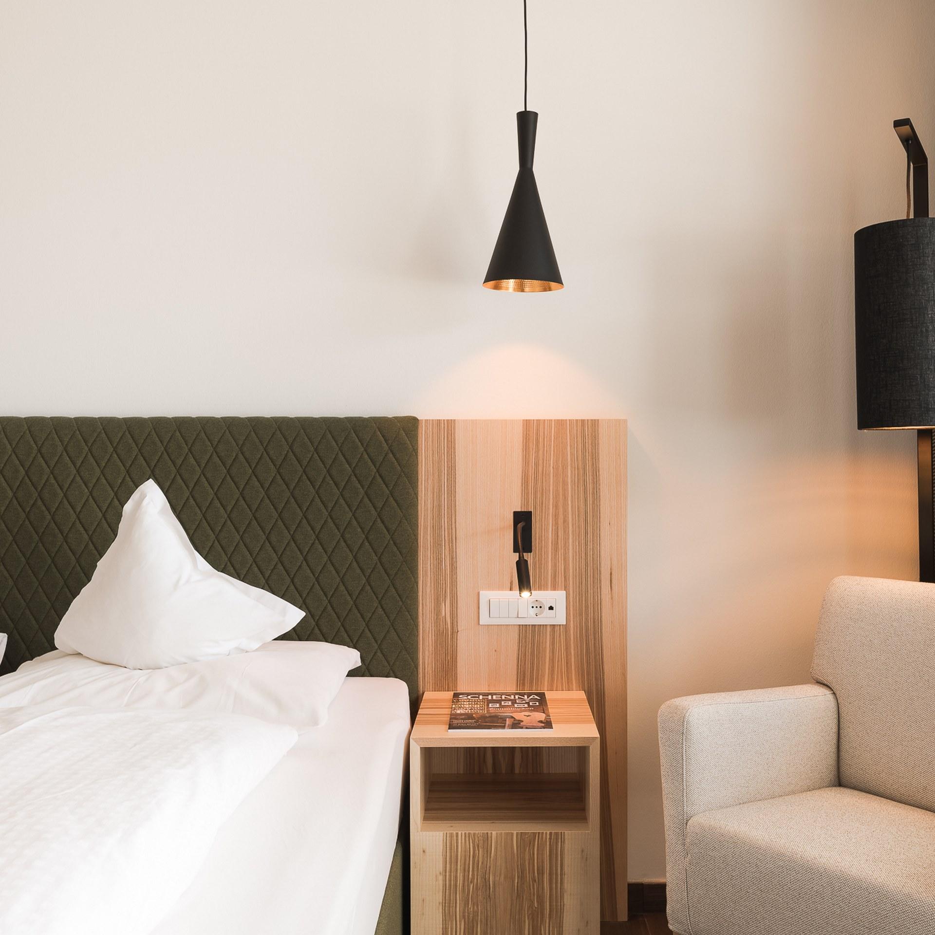 Gemütliches Schlafzimmer mit Bett und Sessel im Alpenpalais Kröll