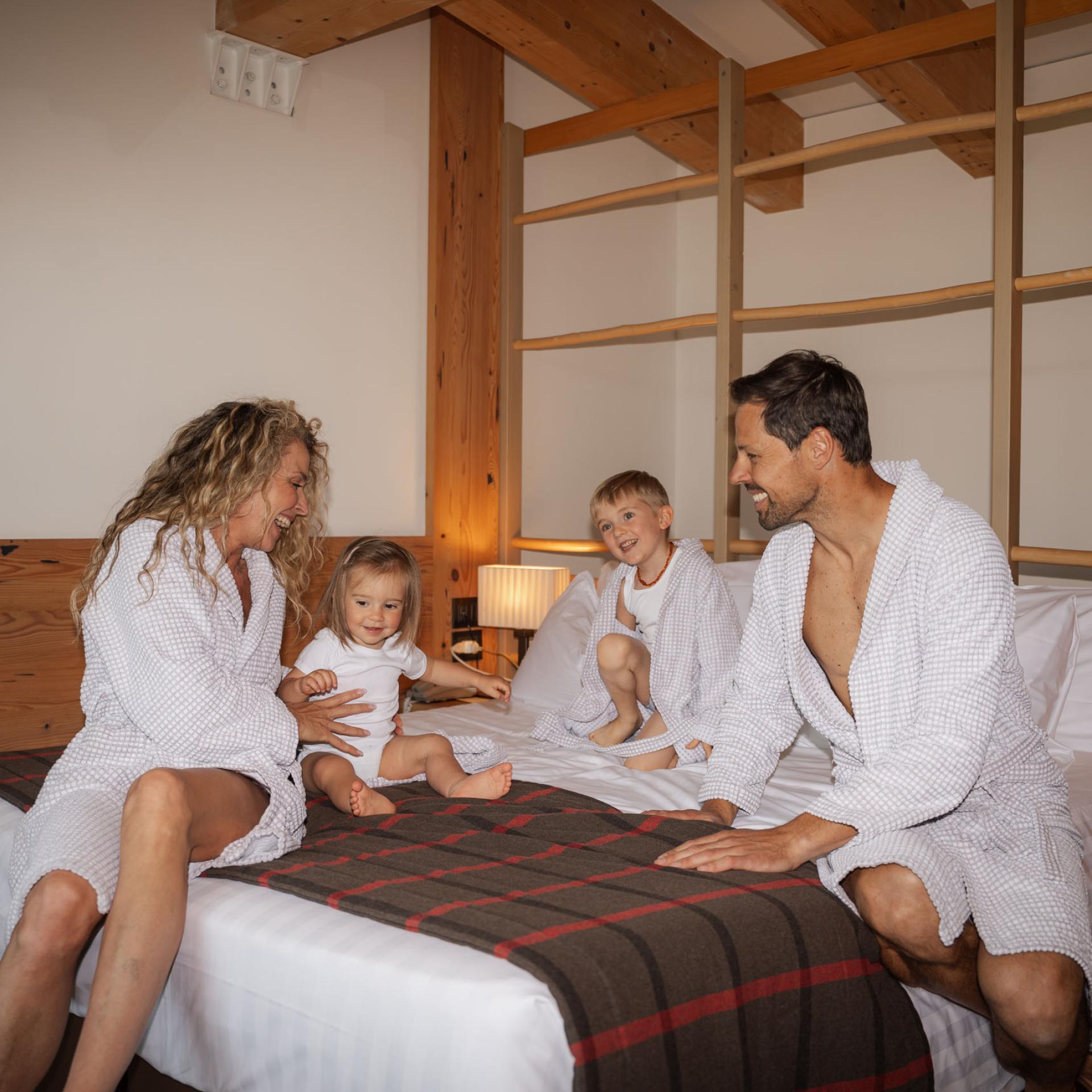 Letto matrimoniale con testiera grigia e parete in legno all'Hotel San Giacomo