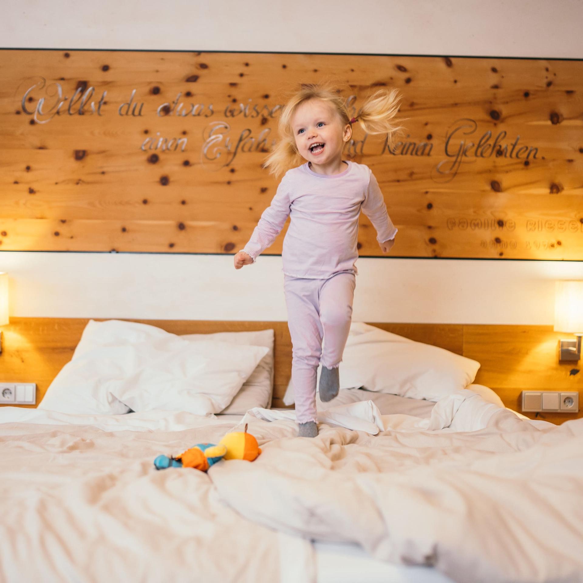 Kind springt auf einem Bett im Familienresort Buchau