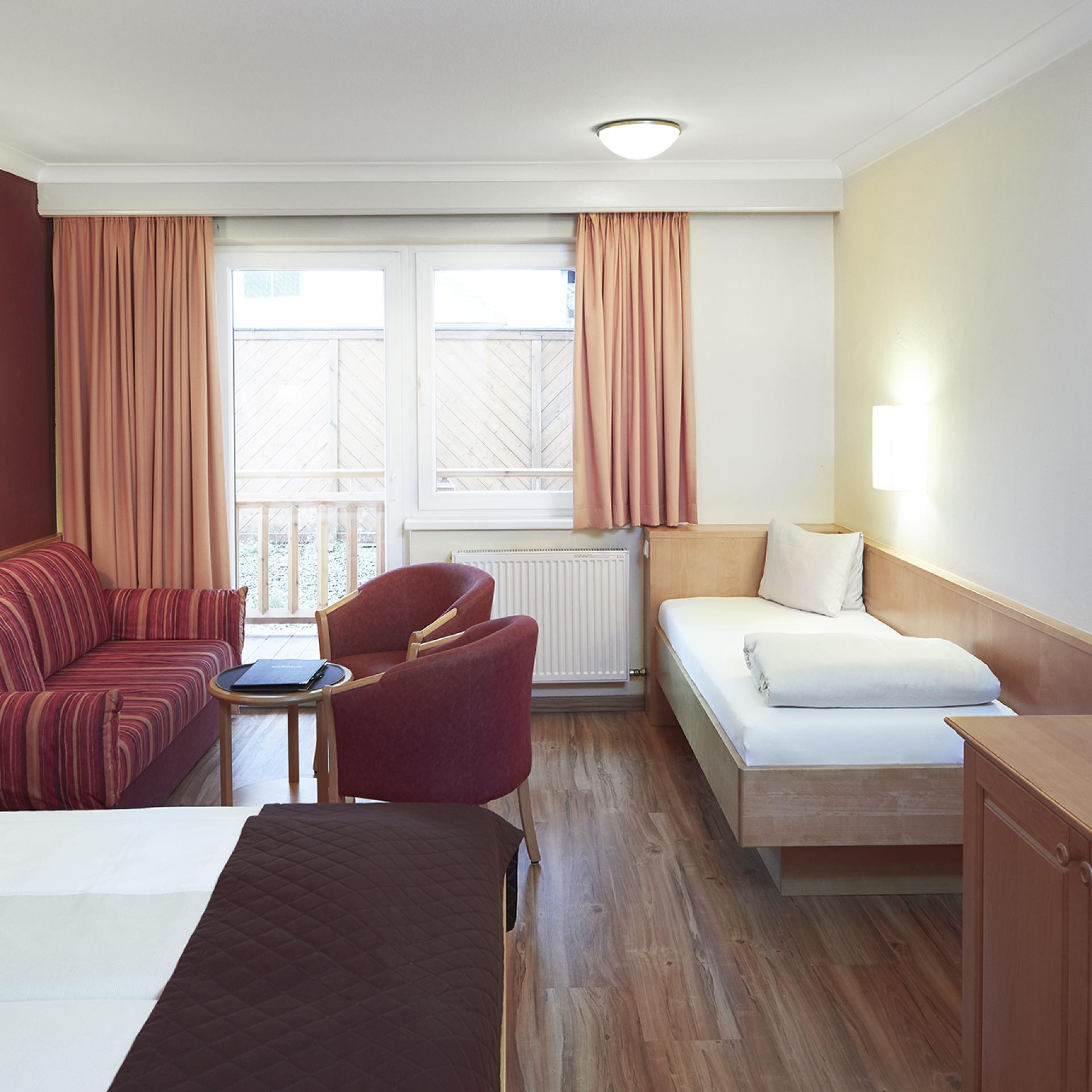 Gemütliches Zimmer im Familienresort Buchau mit Bett, Sofa und Fernseher