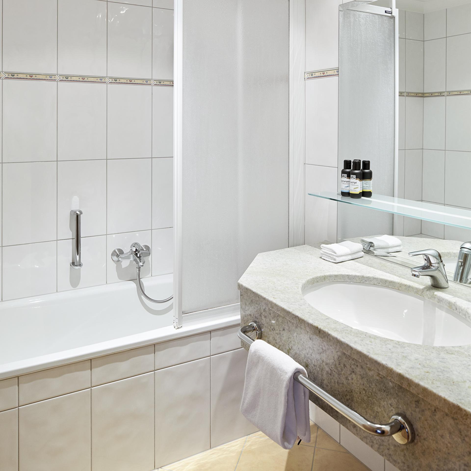 Bathroom with bathtub and sink at Familienresort Buchau