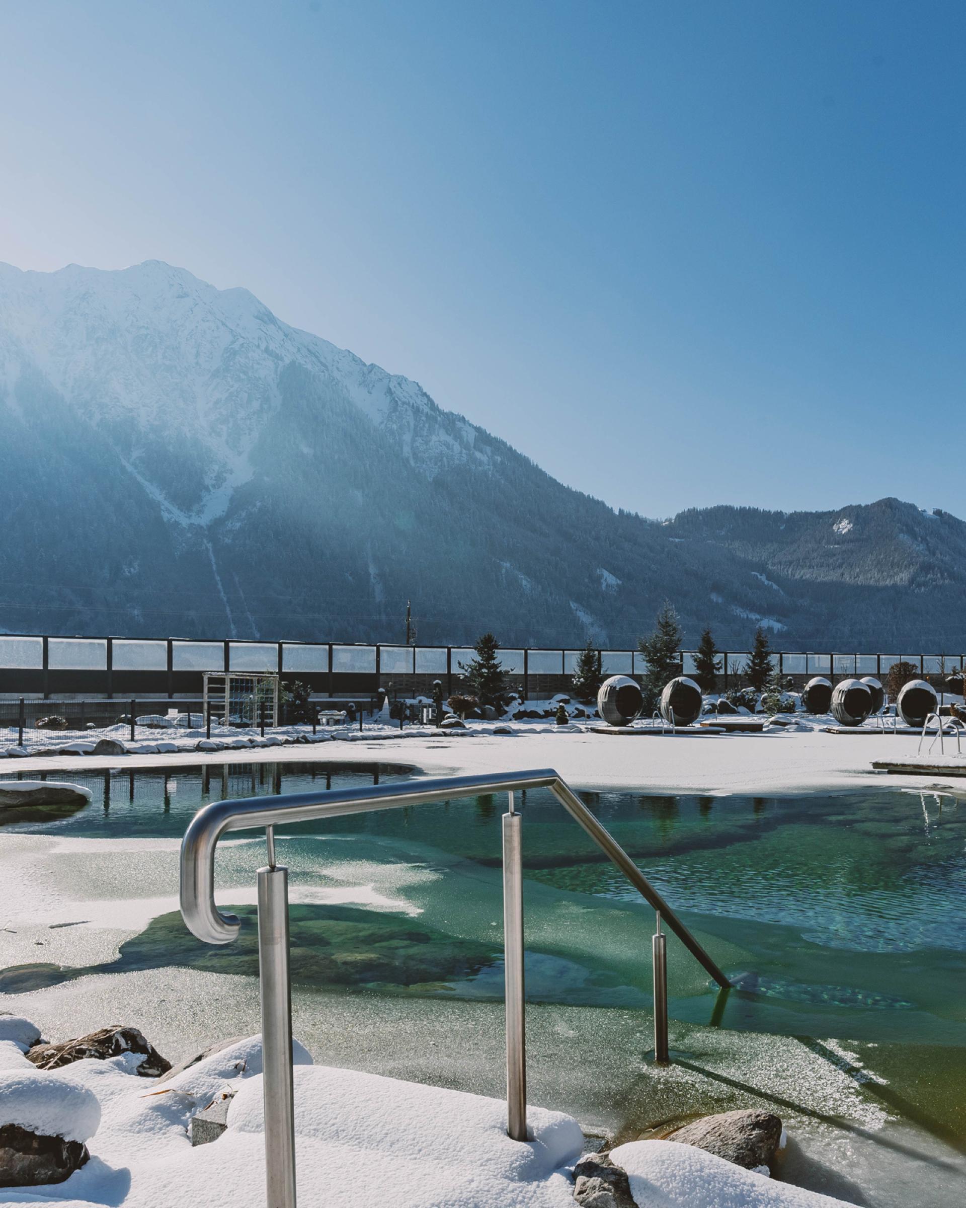 Winterliche Außenpoollandschaft im Familienresort Buchau mit Bergkulisse
