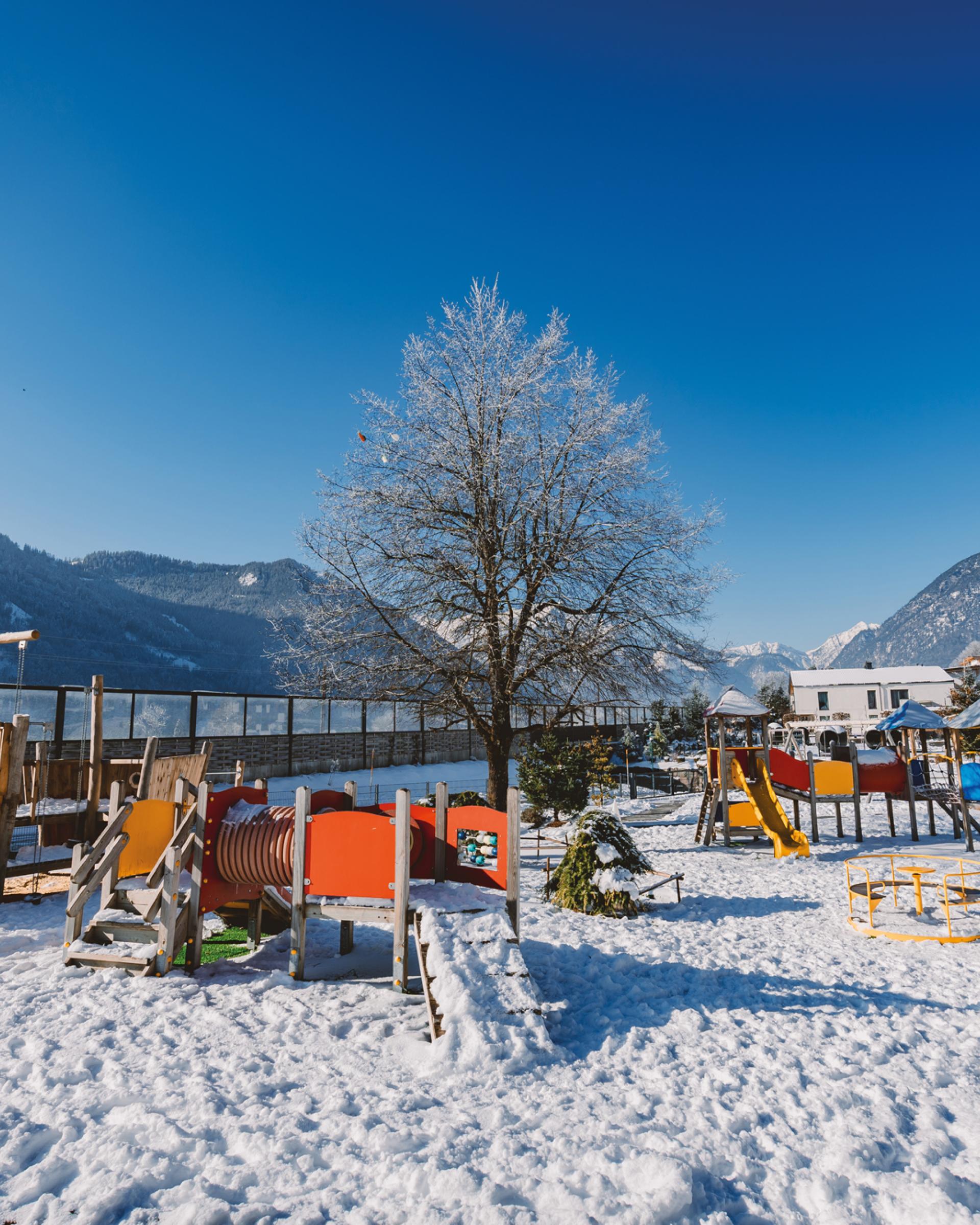 Spielplatz im Familienresort Buchau im Schnee vor Bergkulisse