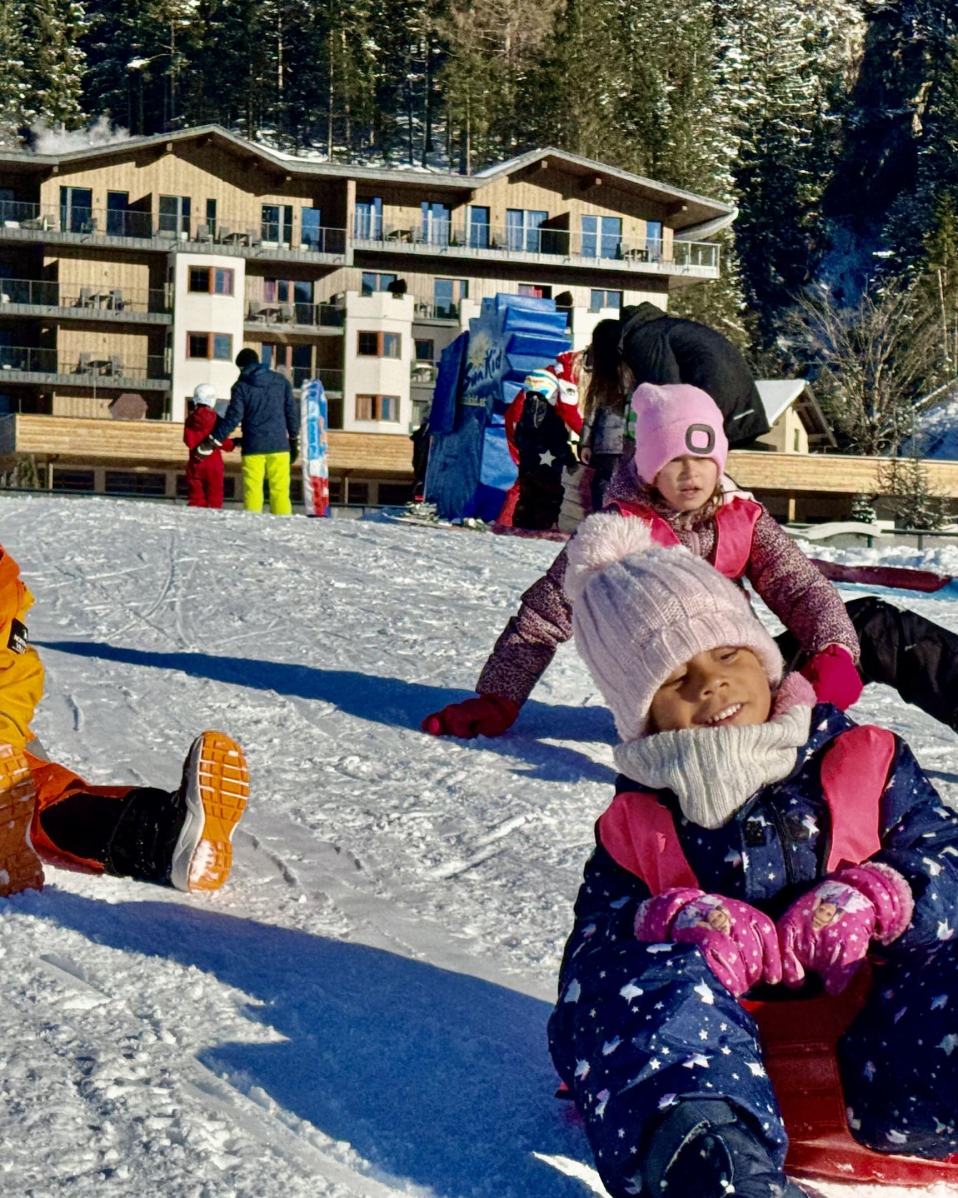 Kinder rodeln im Schnee vor dem Familienresort Buchau