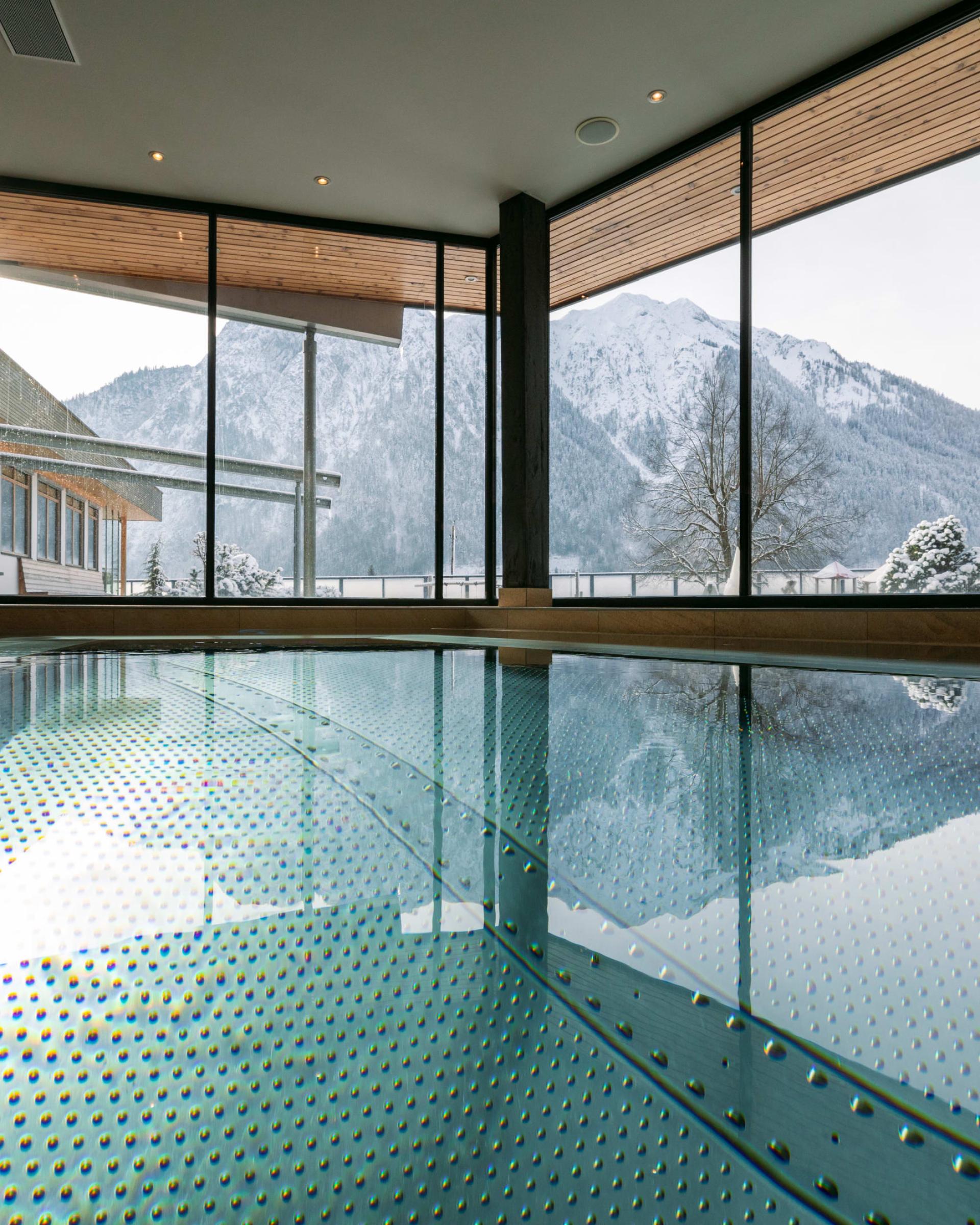 Innenpool im Familienresort Buchau mit Bergblick durch große Fenster