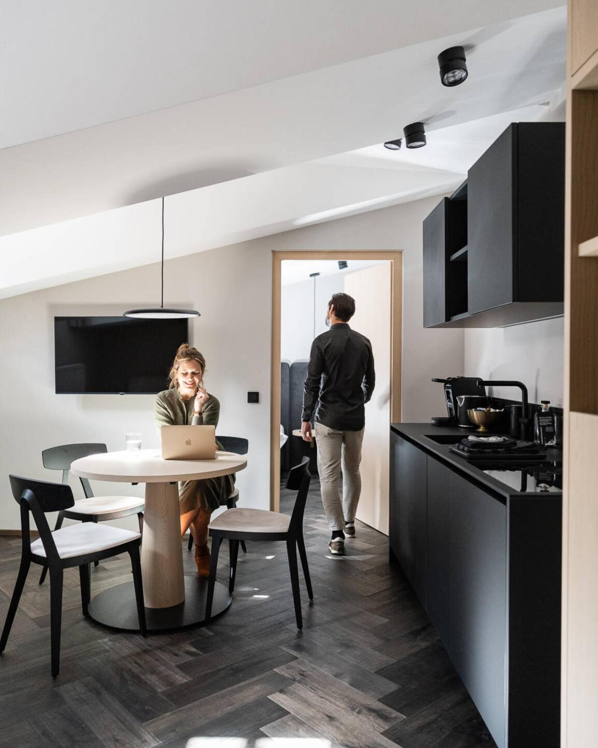 Modern kitchen at Schwarzer Adler with a woman at a laptop and a man in the doorway