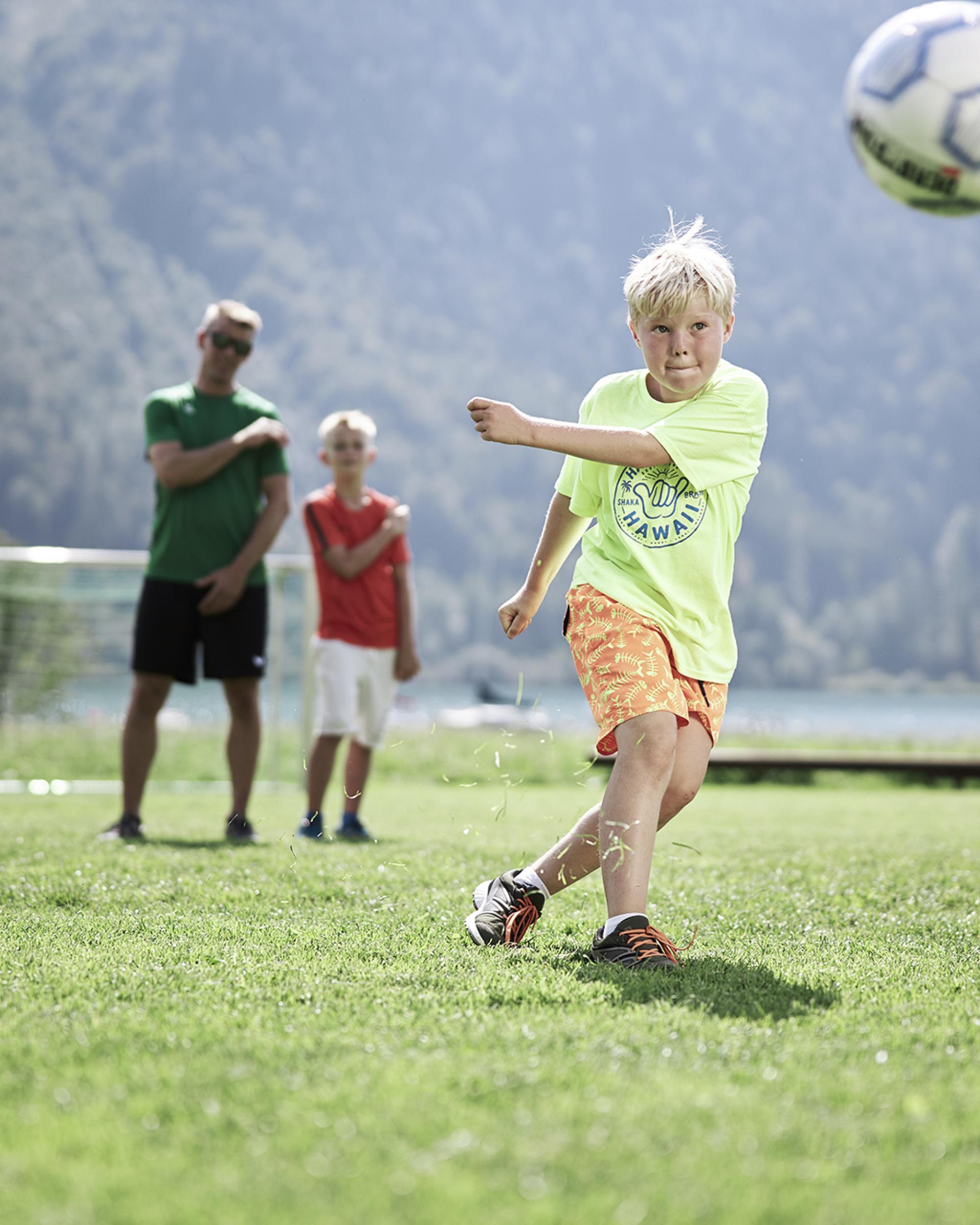 Kind spielt Fußball im Familienresort Buchau mit Bergkulisse