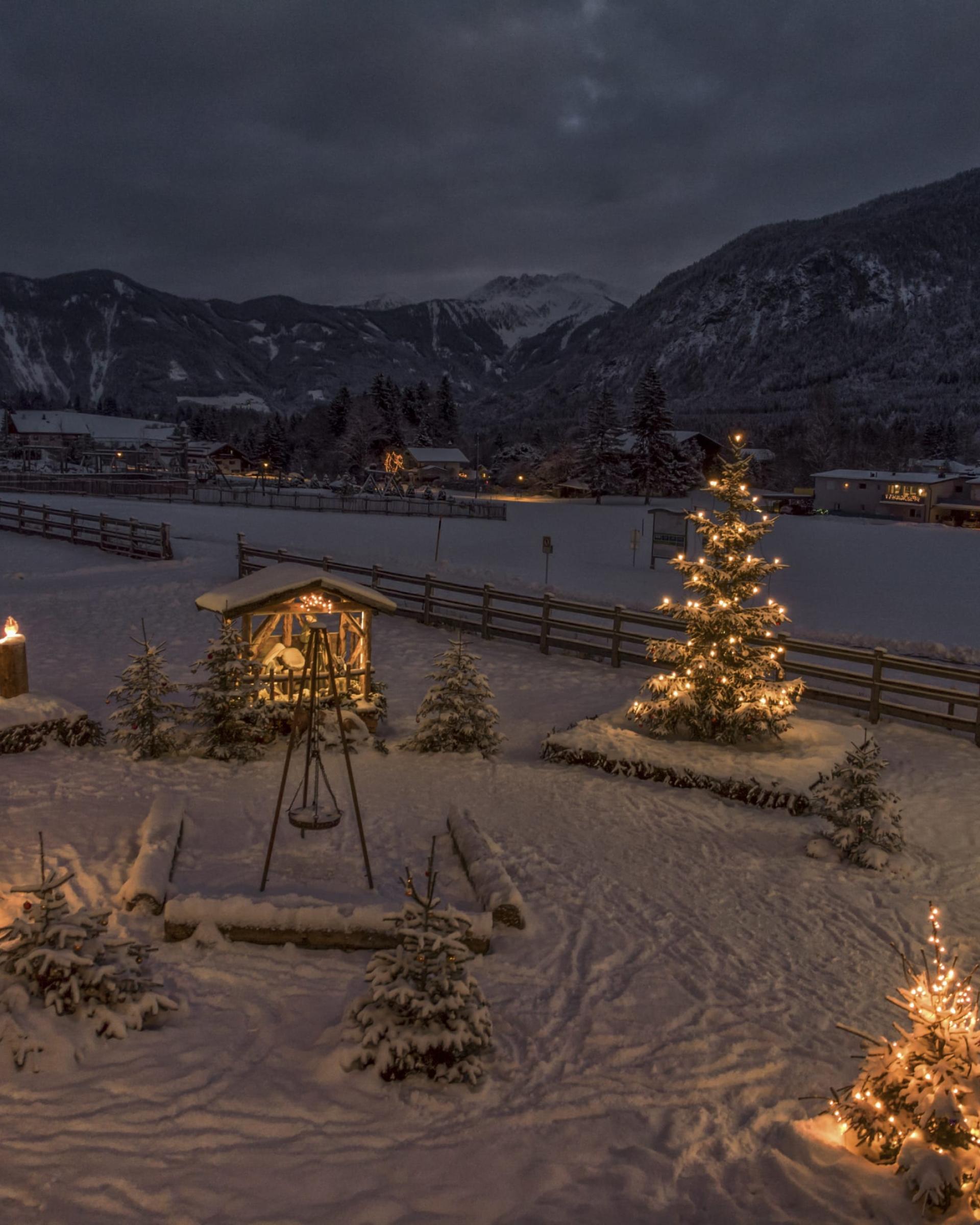 Weihnachtlich beleuchtete verschneite Landschaft im Familienresort Buchau bei Nacht
