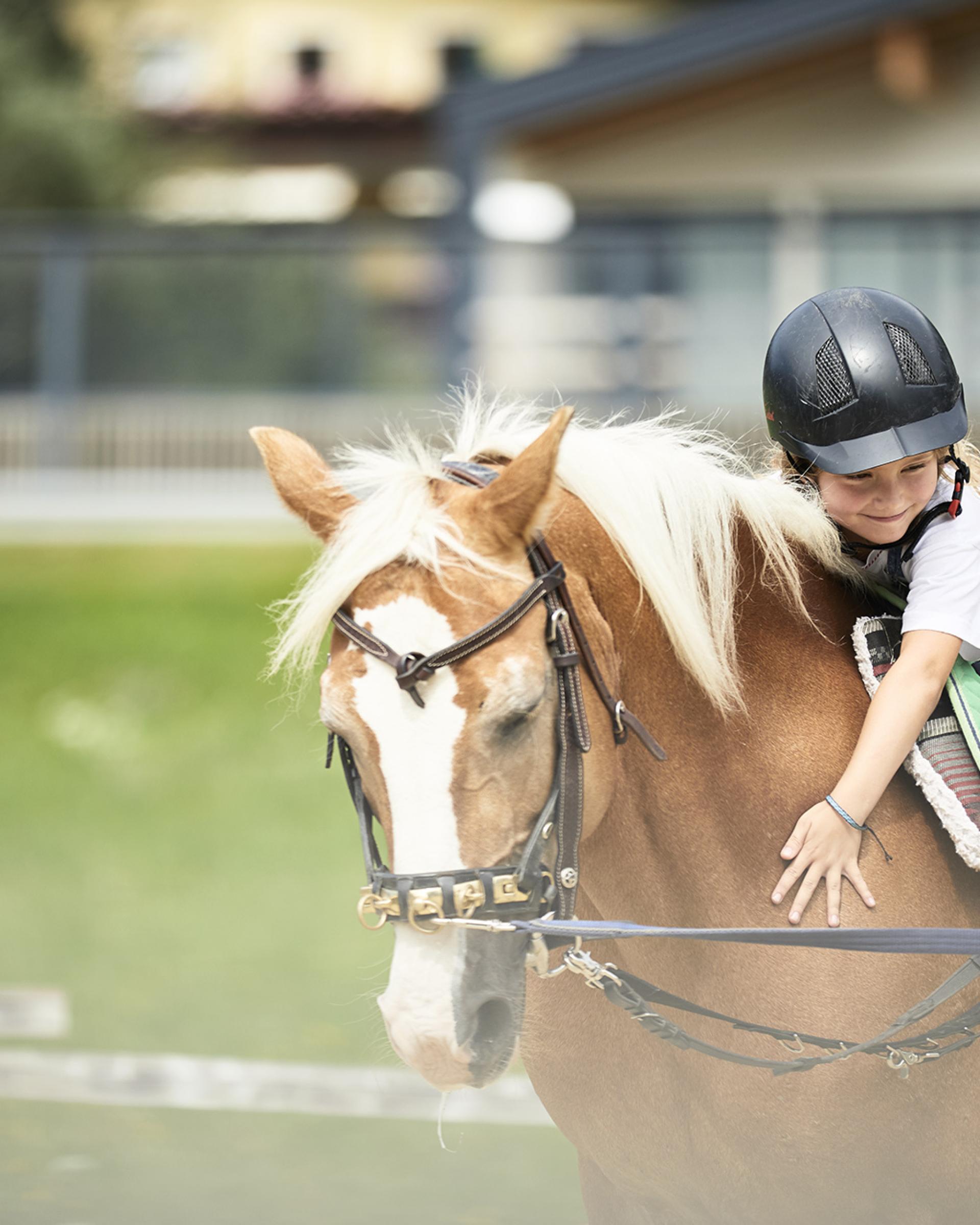Kind reitet Pferd im Familienresort Buchau mit Helm und Freude