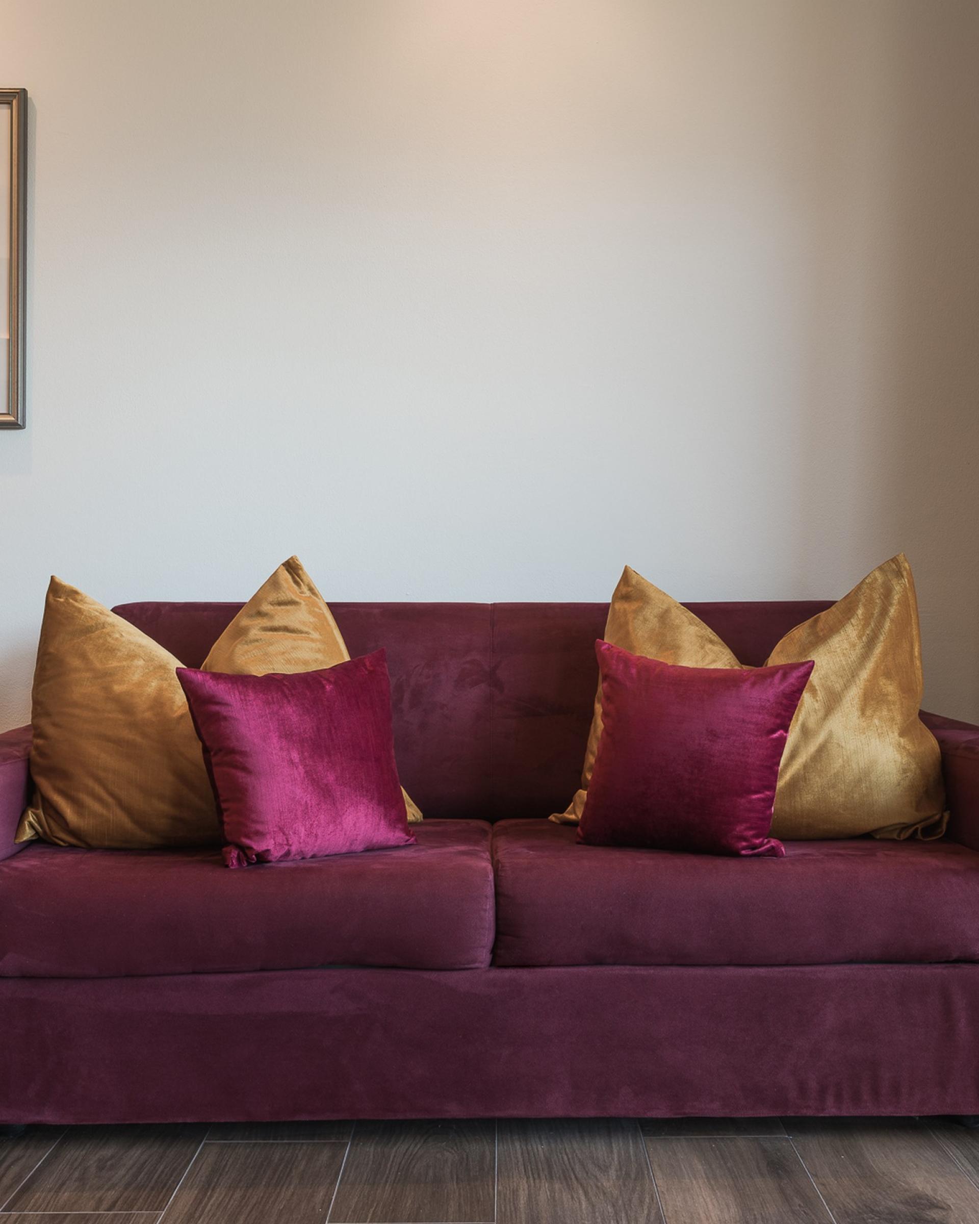 Alpenpalais Kröll Wohnzimmer mit weinrotem Sofa und goldenen Kissen