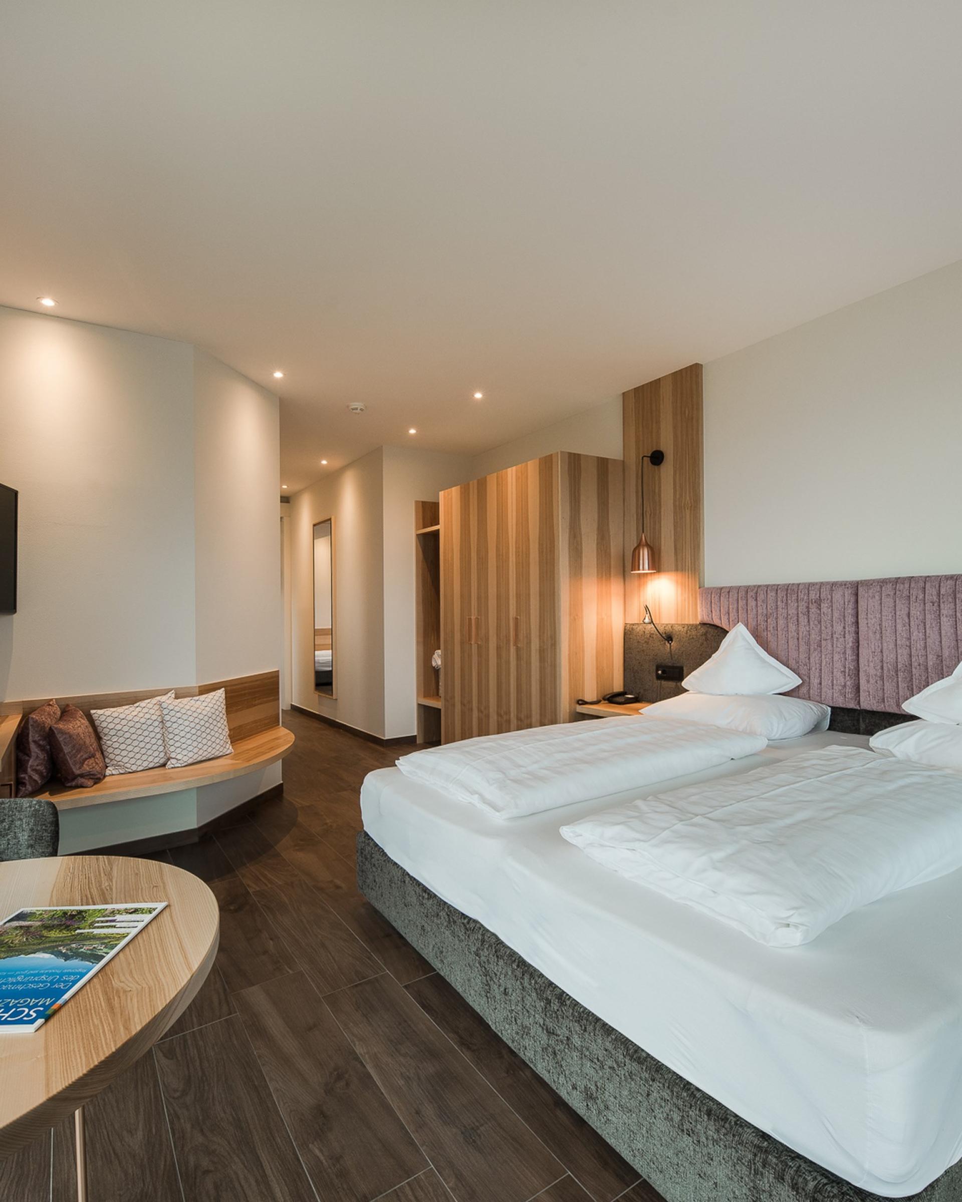 Modernes Schlafzimmer im Alpenpalais Kröll mit Doppelbett und Sitzecke