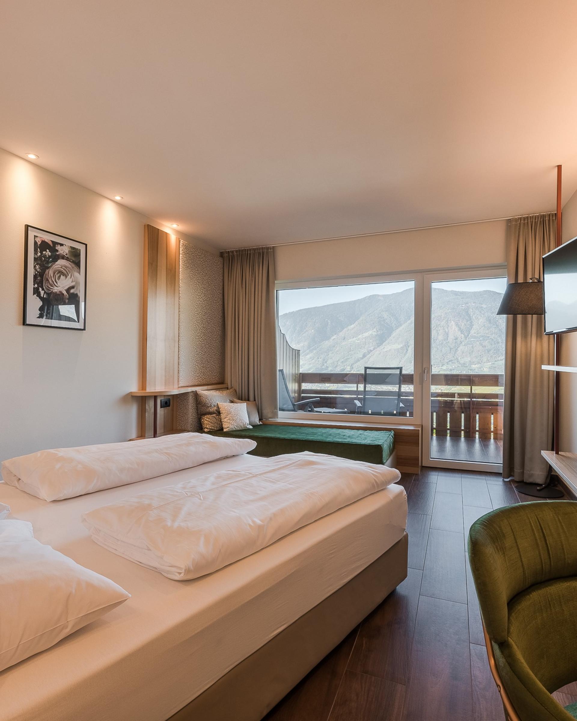 Hell eingerichtetes Zimmer mit Doppelbett und Balkon im Alpenpalais Kröll