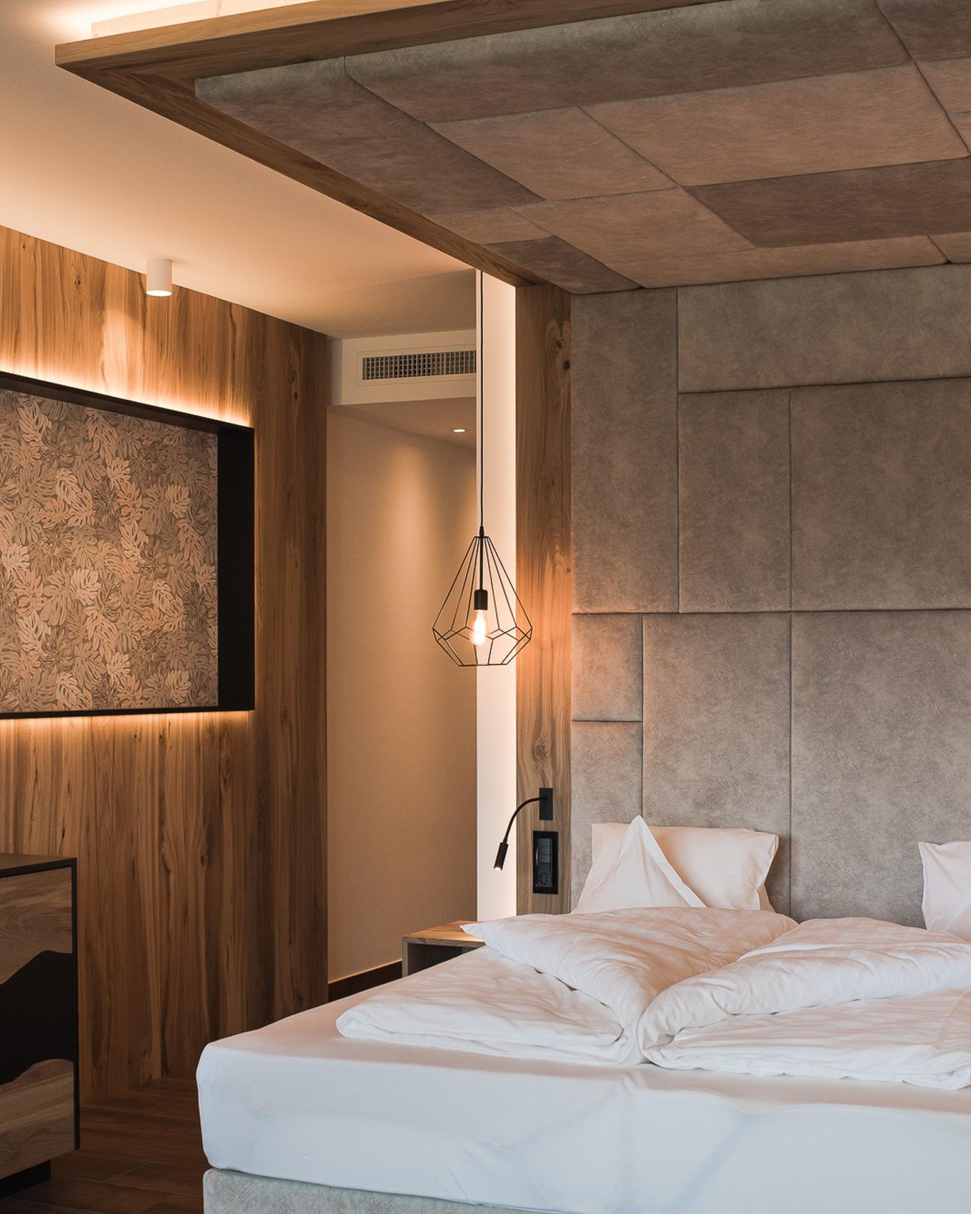 Modernes Schlafzimmer im Alpenpalais Kröll mit Holz- und Steindesign.