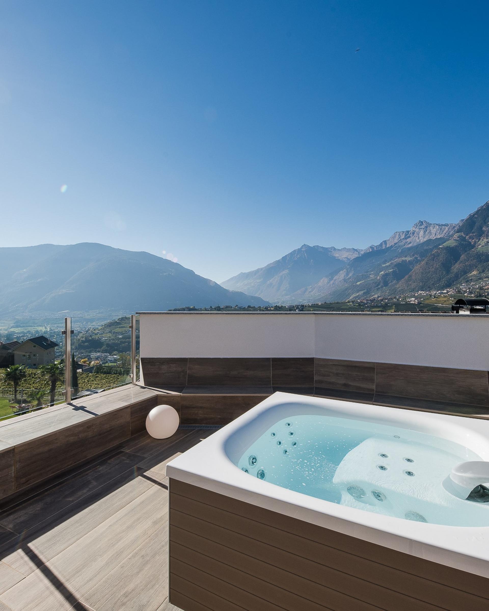 Alpenpalais Kröll mit Whirlpool auf Terrasse und Bergblick bei Sonnenschein