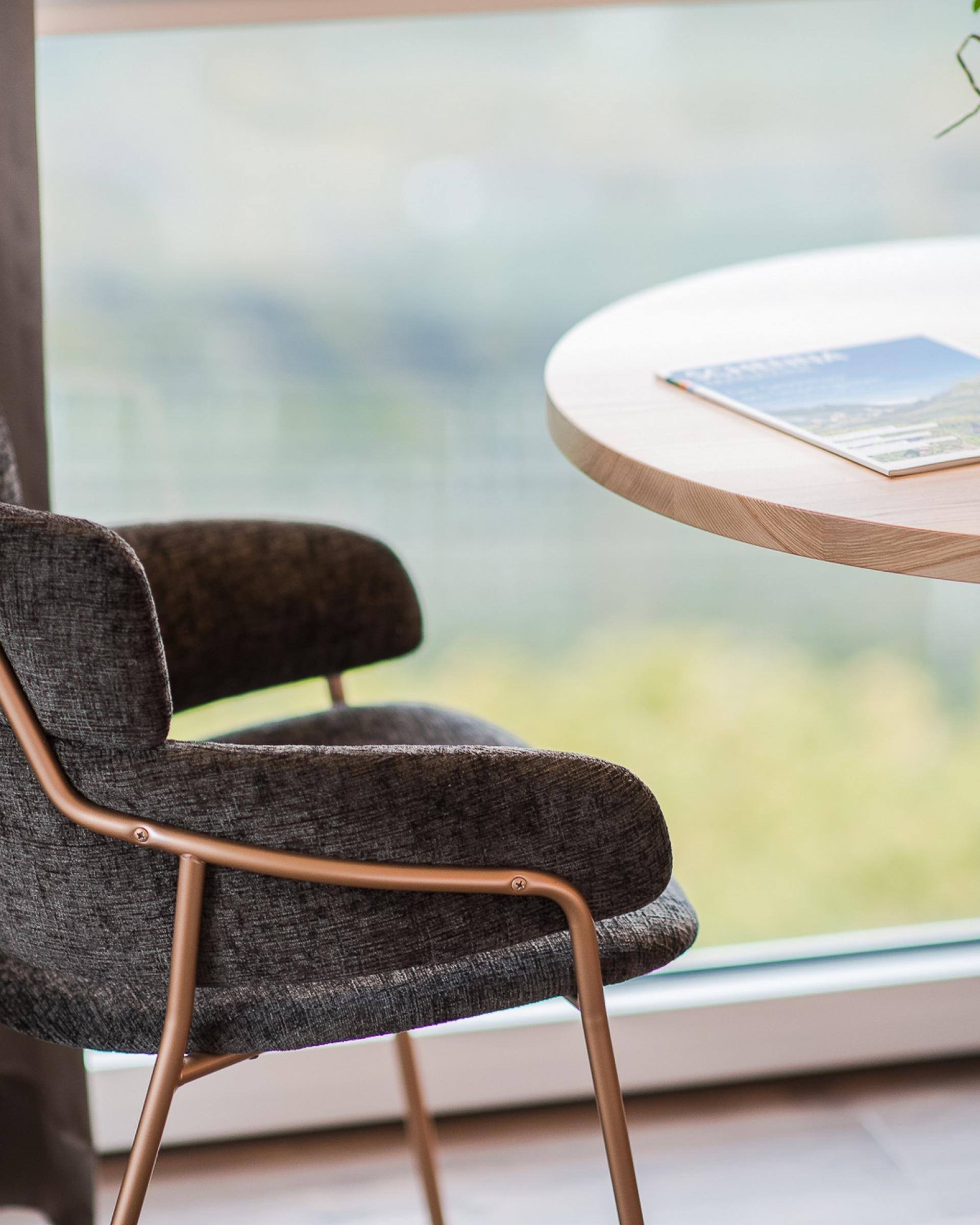 Gemütlicher Stuhl neben Tisch mit Alpenpalais Kröll Broschüre am Fenster