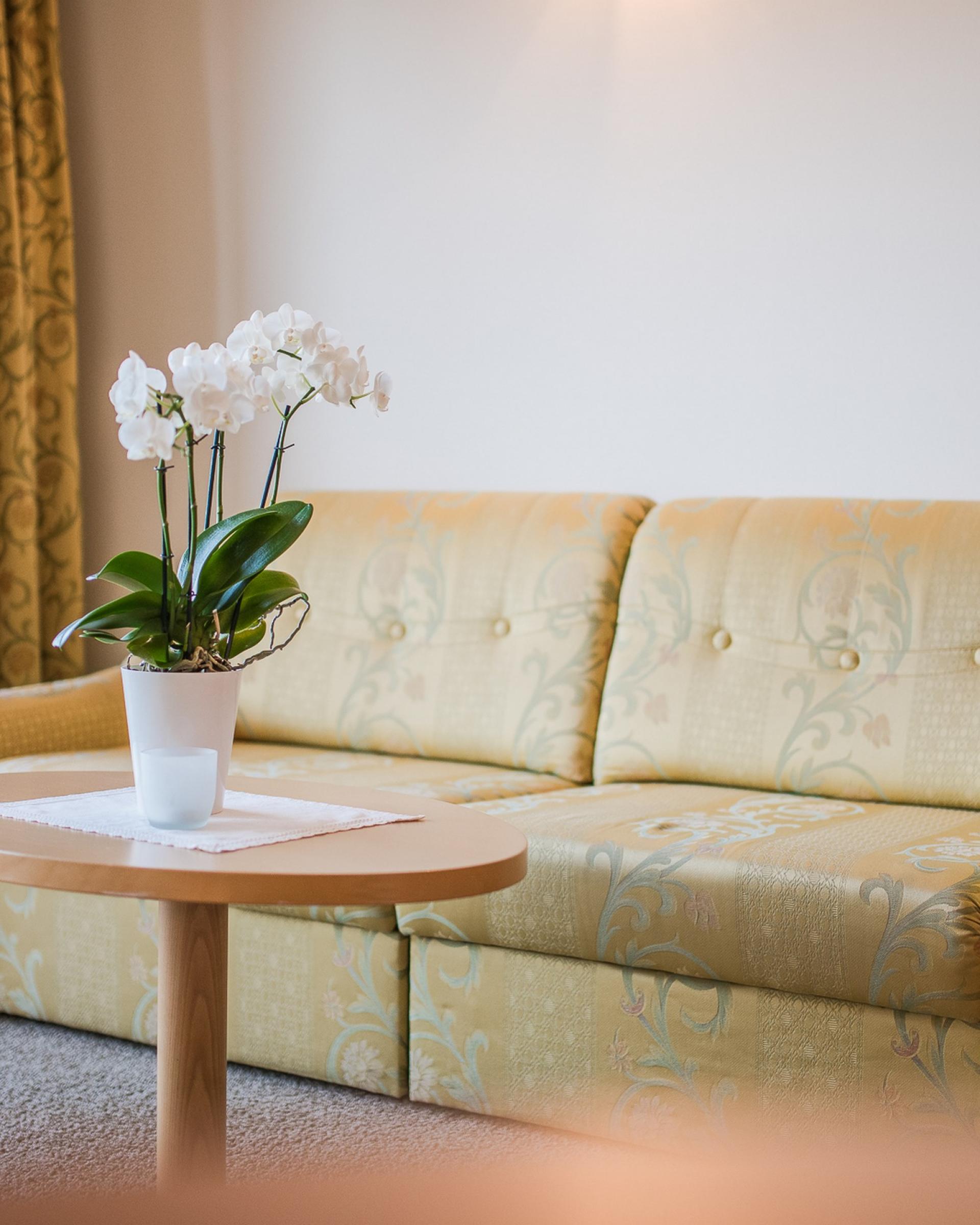Gemütliche Sitzecke im Alpenpalais Kröll mit Sofa und Blumentisch