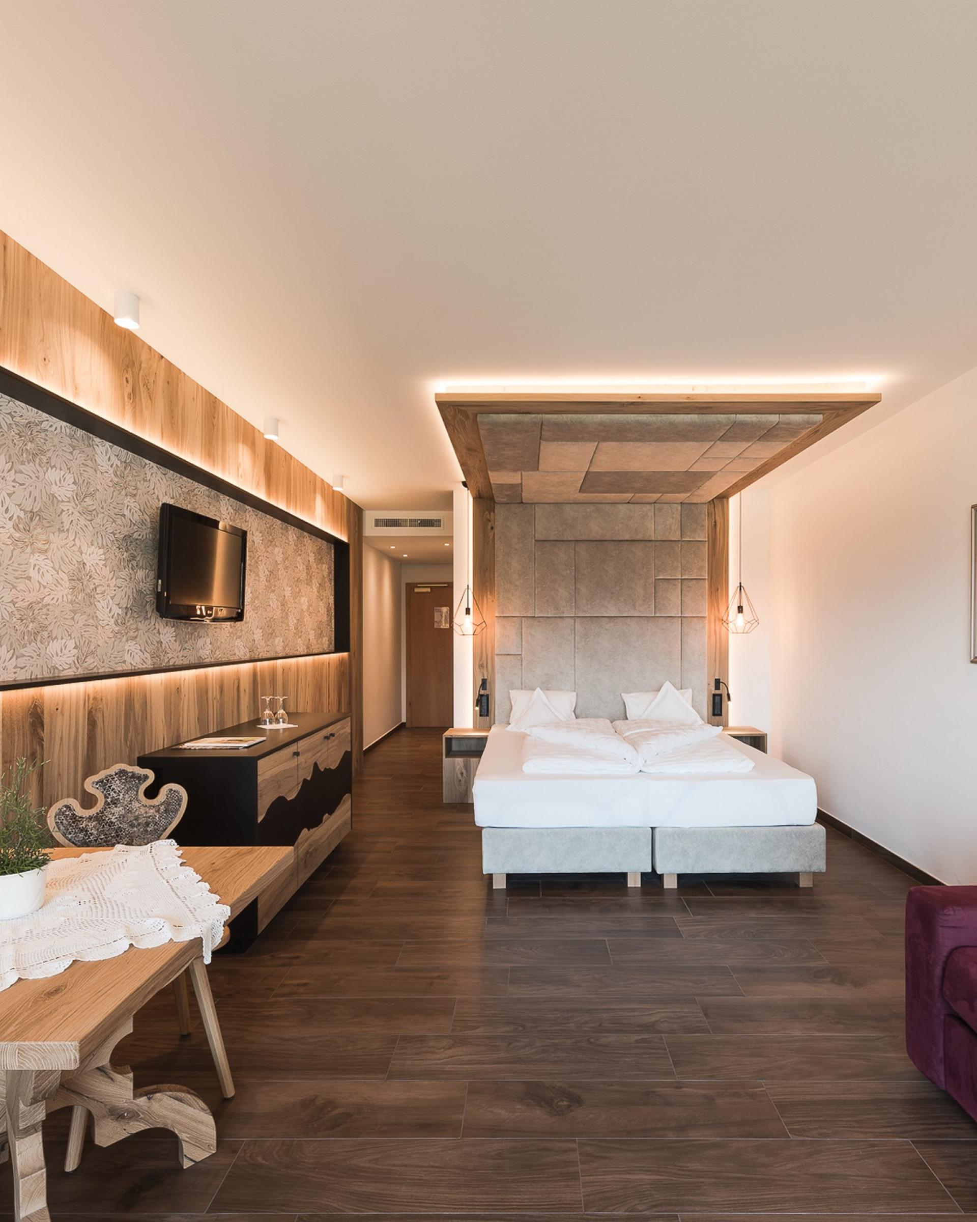 Modernes Hotelzimmer im Alpenpalais Kröll mit Doppelbett und Sitzbereich