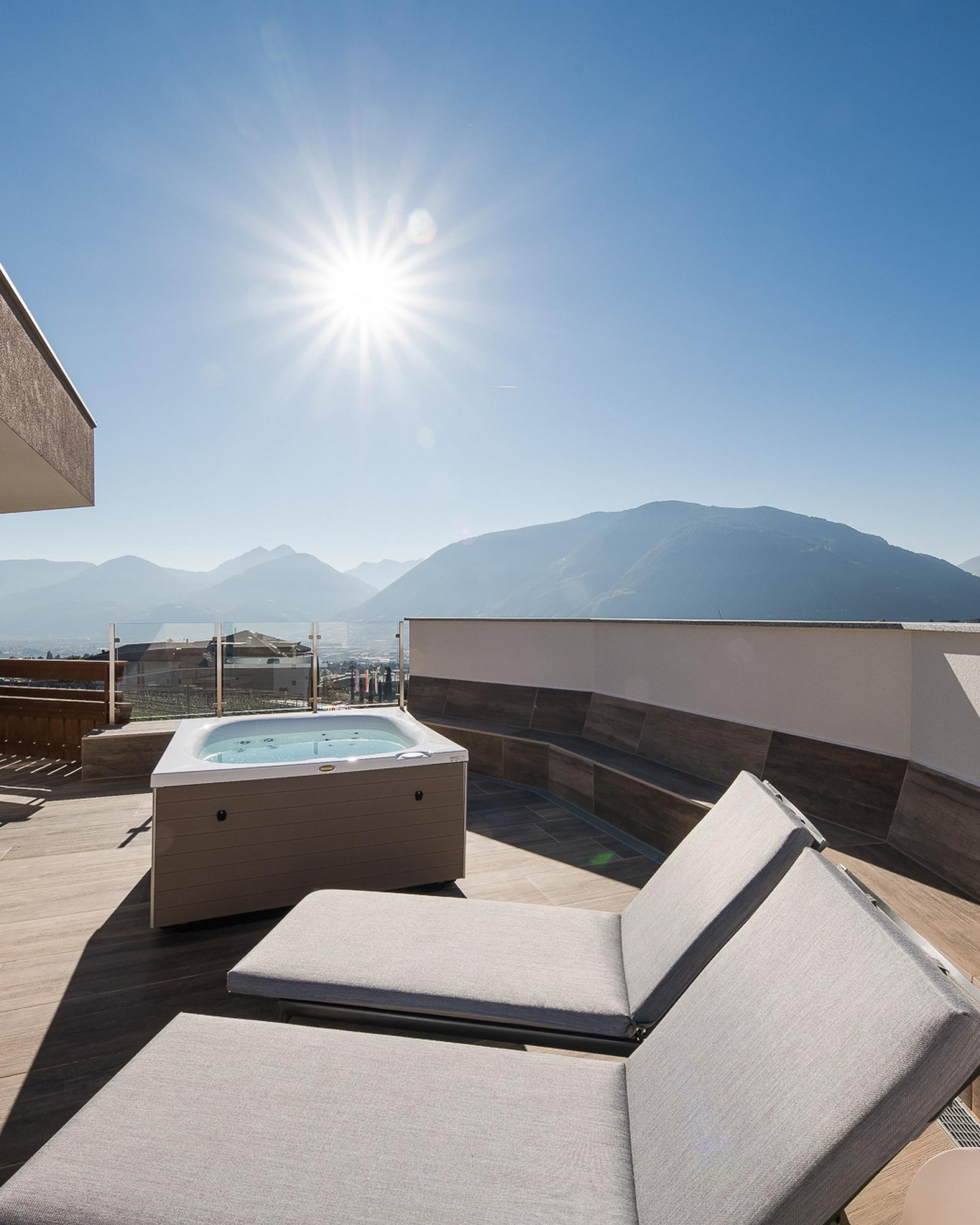 Terrasse mit Whirlpool und Liegestühlen im Alpenpalais Kröll vor Bergkulisse