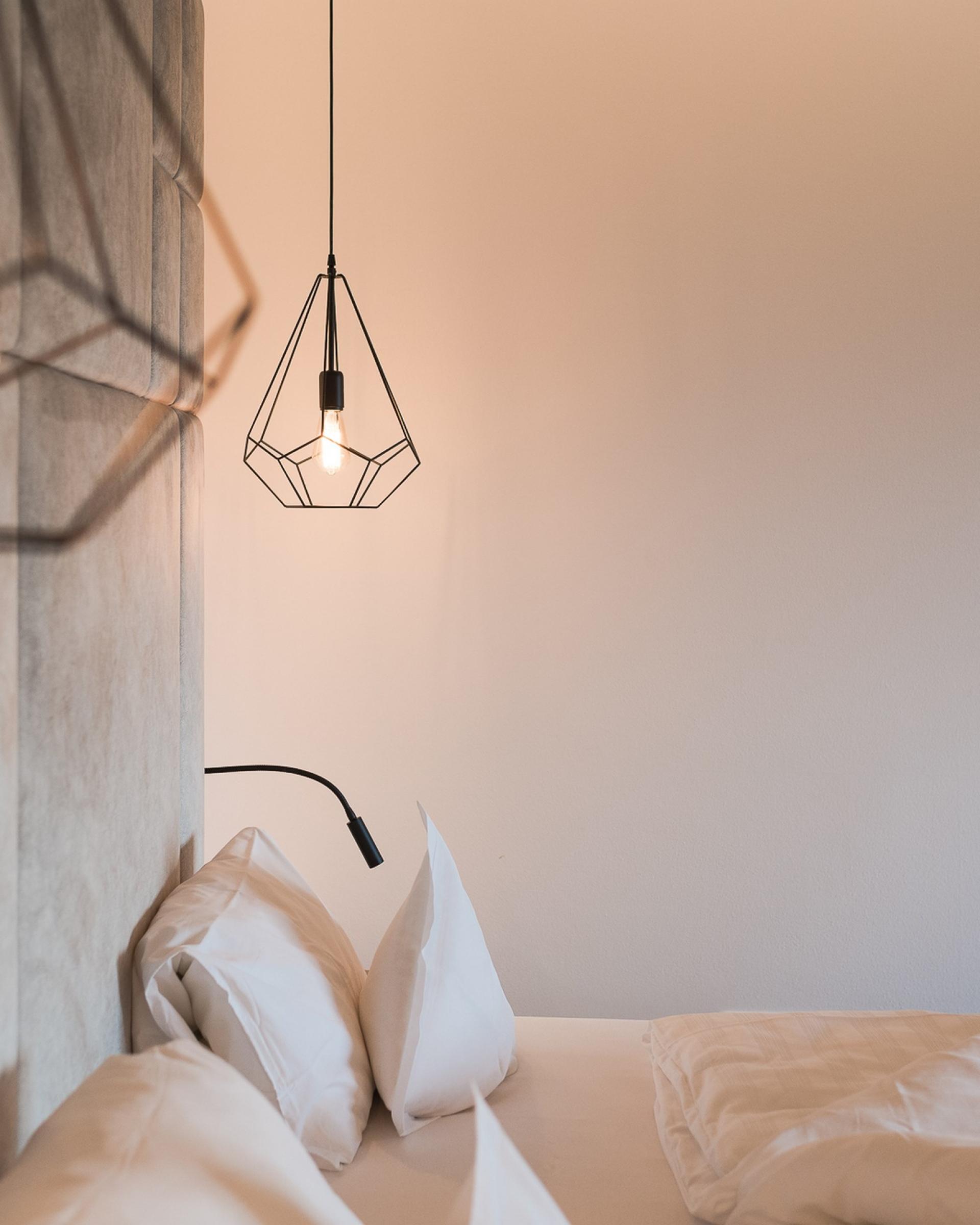 Schlafzimmer mit modernen Lampen im Alpenpalais Kröll