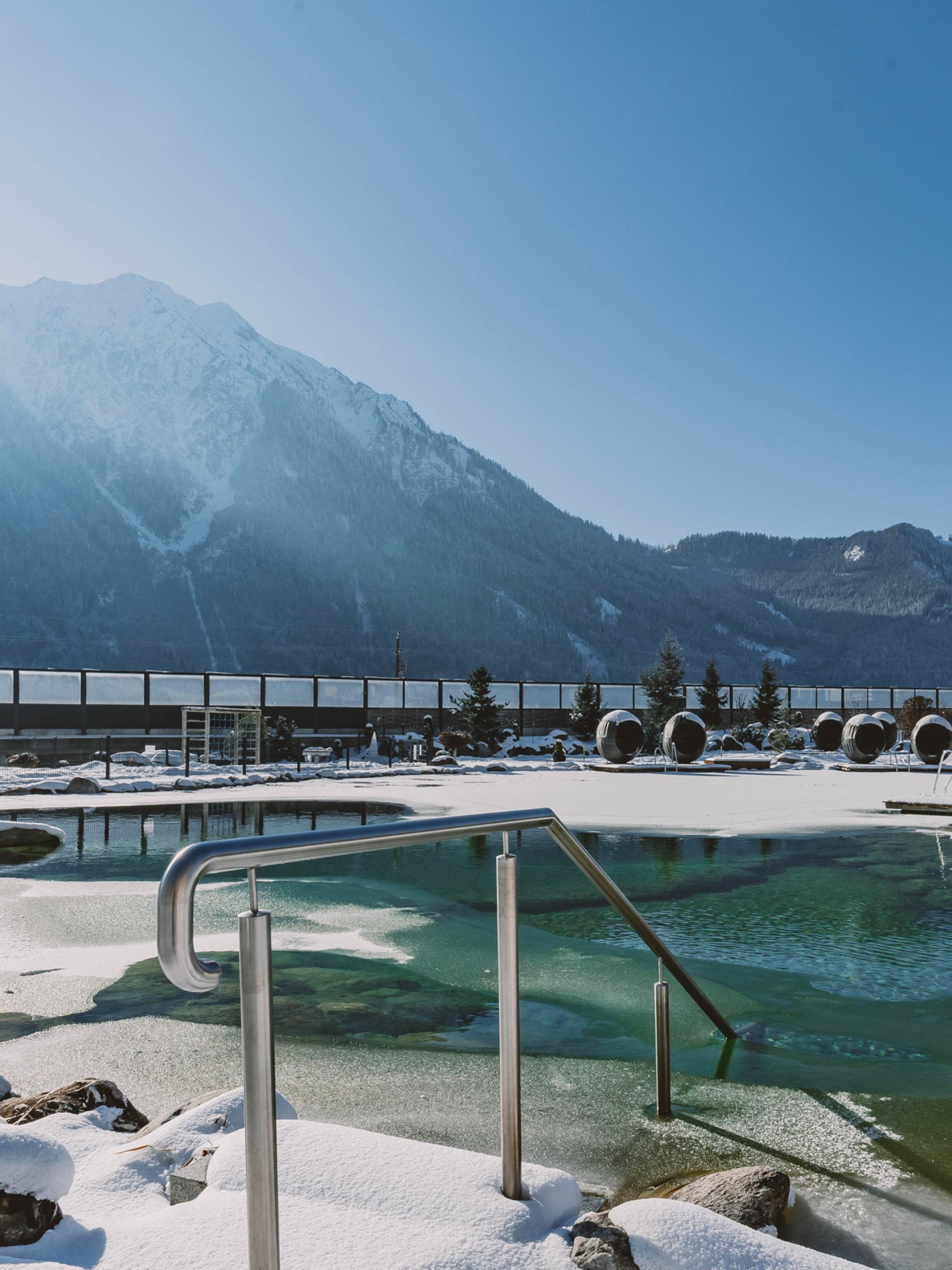 Winter outdoor pool at Familienresort Buchau with mountain backdrop