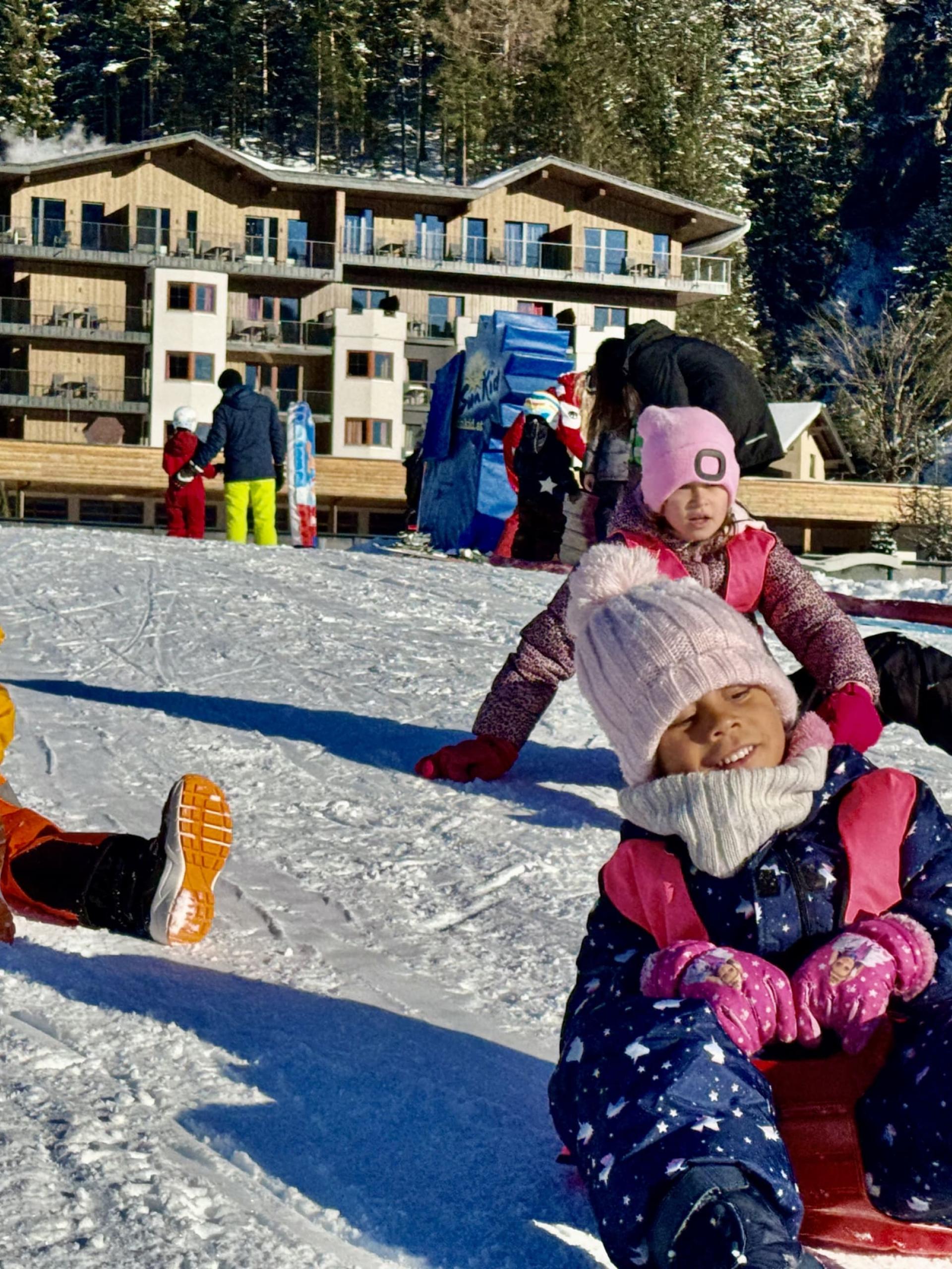 Kinder rodeln im Schnee vor dem Familienresort Buchau