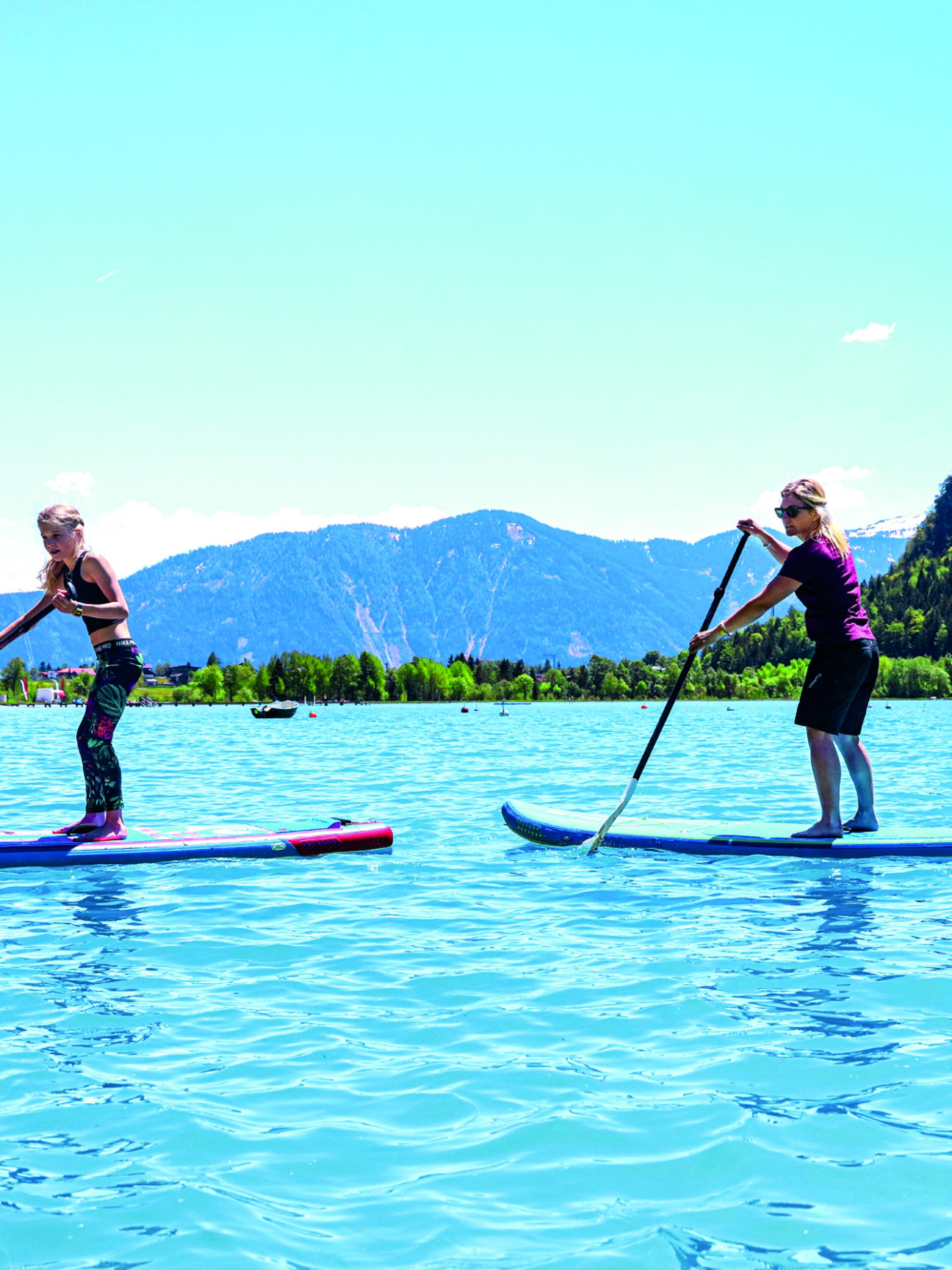 Zwei Personen paddeln auf Stehpaddelbrettern auf dem Wasser im Familienresort Buchau
