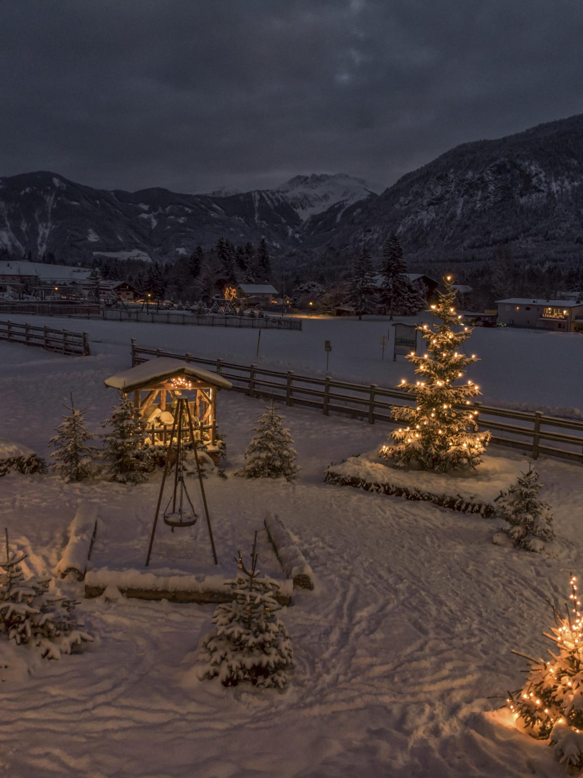 Weihnachtlich beleuchtete verschneite Landschaft im Familienresort Buchau bei Nacht