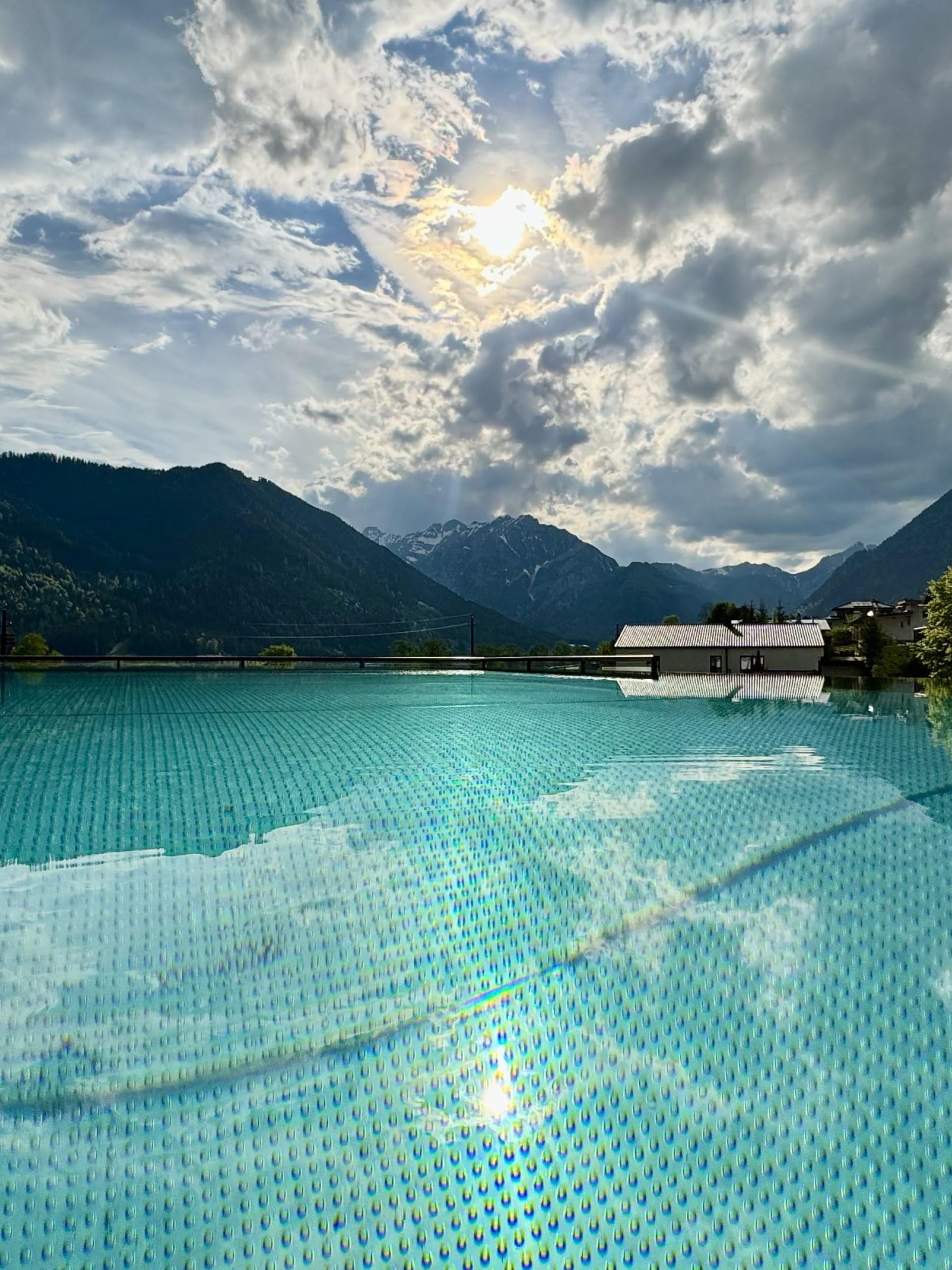 Außenpool mit Bergblick im Familienresort Buchau bei bewölktem Himmel