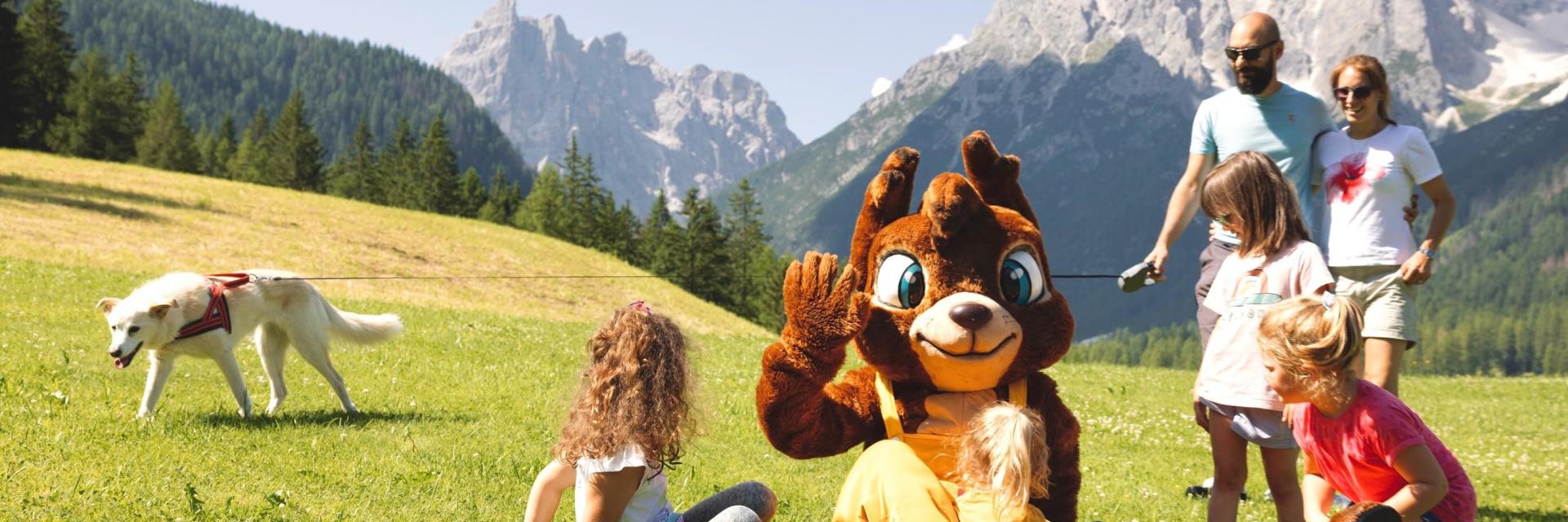 Hotel Rainer: family with a mascot and dog in a mountain meadow
