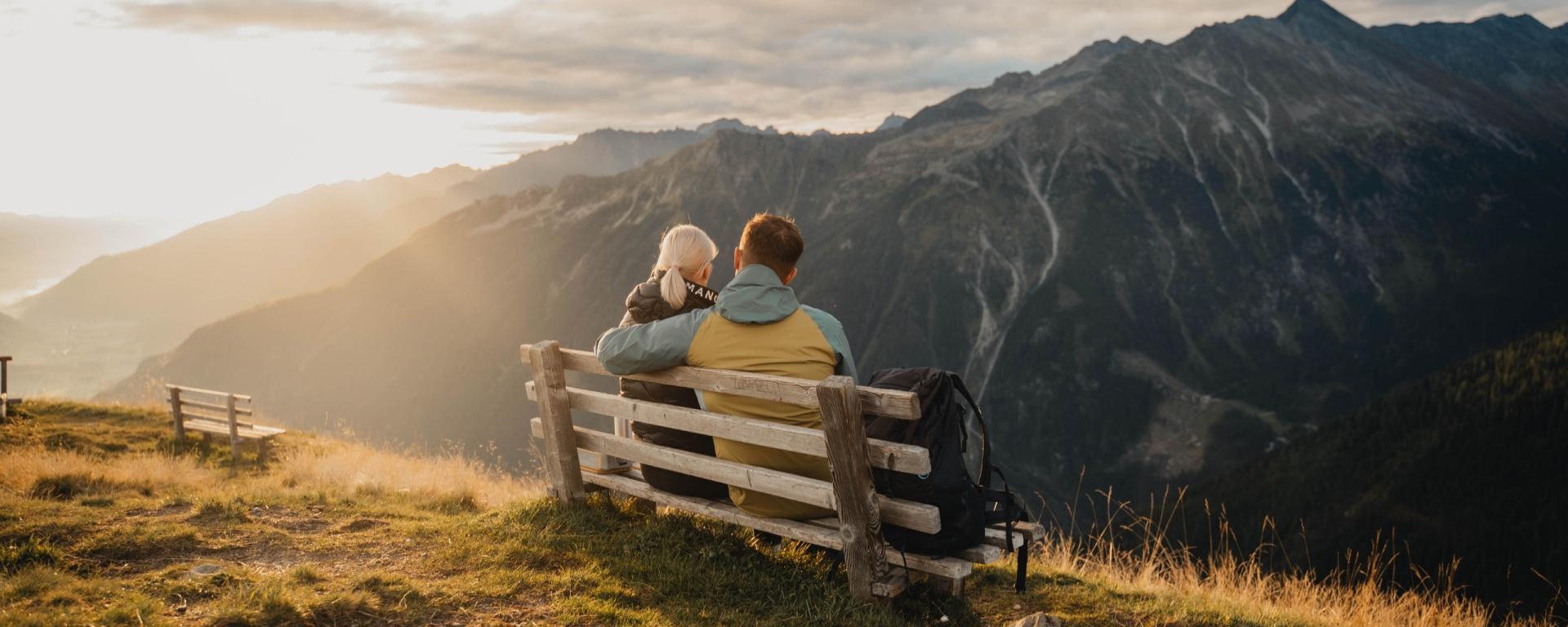 Paar auf Bank mit Bergblick bei Sonnenuntergang nahe Hotel Gassner **** Superior