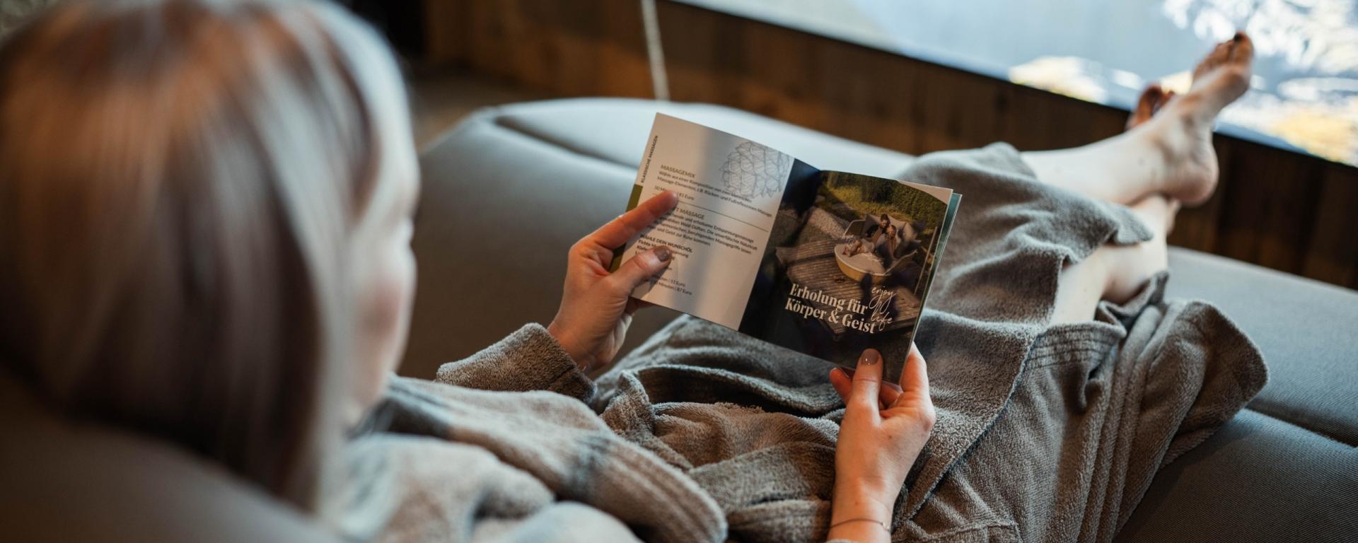 Entspannte Frau liest Magazin im Hotel Gassner **** Superior in Bademantel