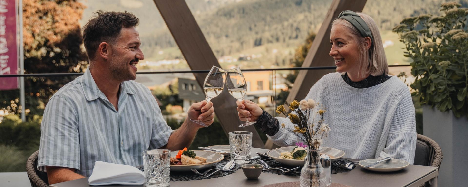 Paar genießt Essen und stoßen im Hotel Gassner **** Superior an