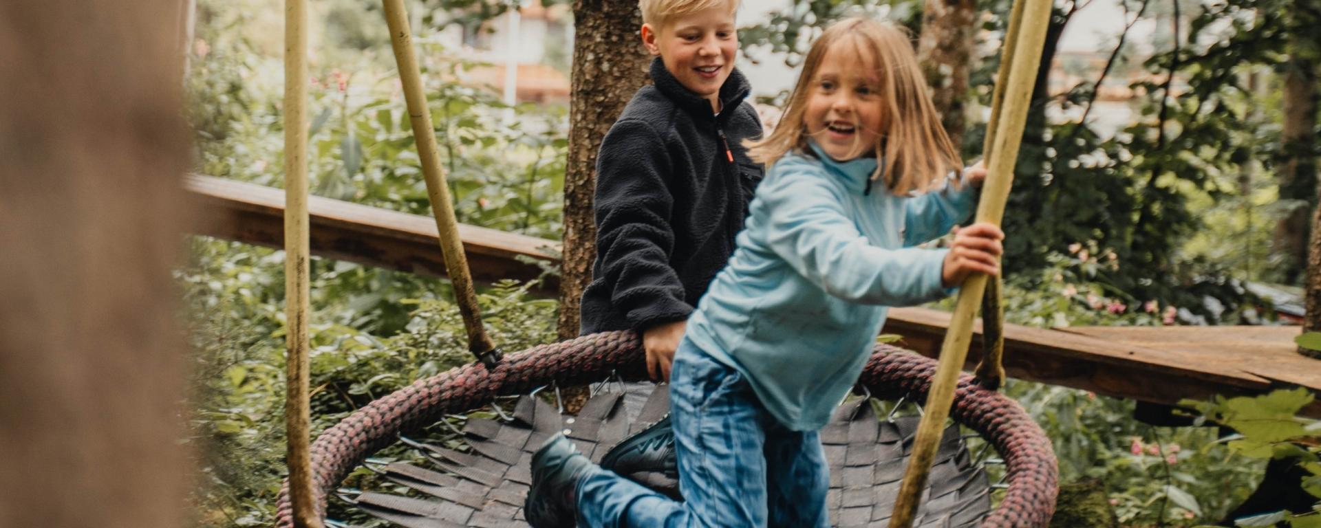 Kinder spielen auf einer Schaukel im Hotel Gassner **** Superior Garten