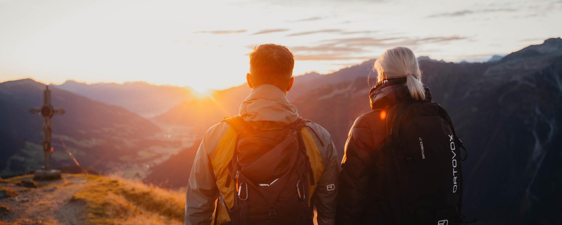 Paar mit Rucksäcken genießt Sonnenuntergang in den Bergen nahe Hotel Gassner **** Superior
