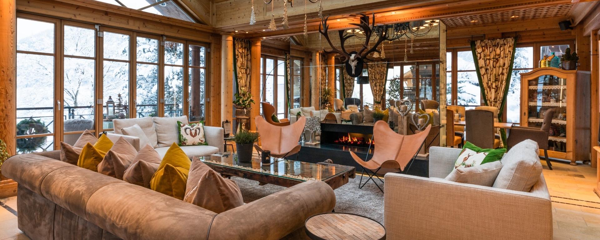 Wohnzimmer im Hotel Gassner mit gemütlicher Couch, Kamin und Schneekulisse im Hintergrund