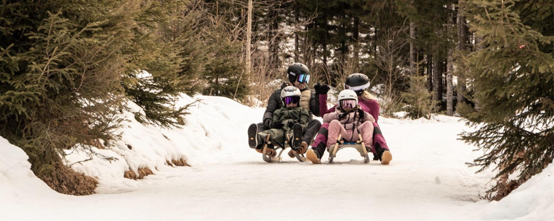Familie auf zwei Schlitten genießr Rodelspaß in der Ferienregion Nationalpark Hohe Tauern
