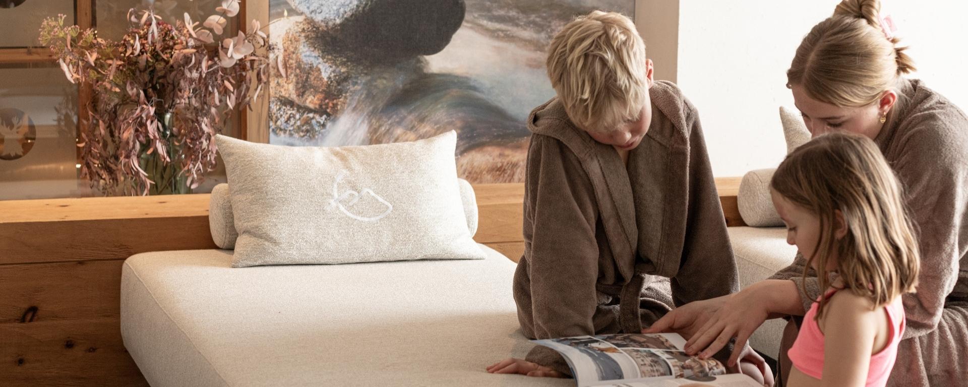 Drei Kinder blättern durch das Wintermagazin im Familienruheraum vom Hotel Gassner