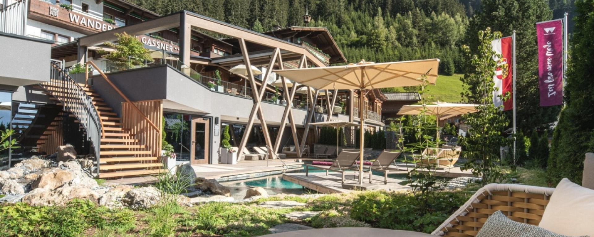 Außenbereich mit Pool und Sonnenschirmen im Hotel Gassner **** Superior vor Bergwald