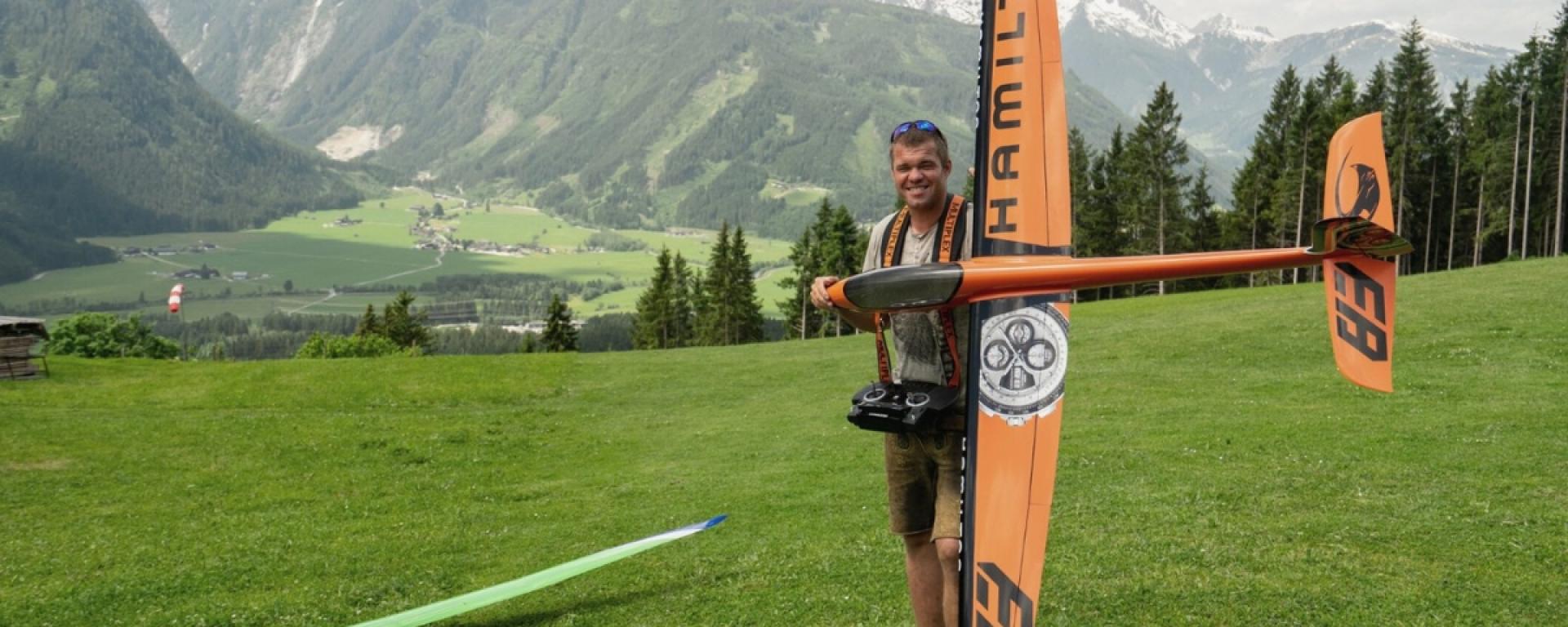 Hotel Gassner **** Superior: Mann hält Modellflugzeug vor Alpenwiesen mit Bergen