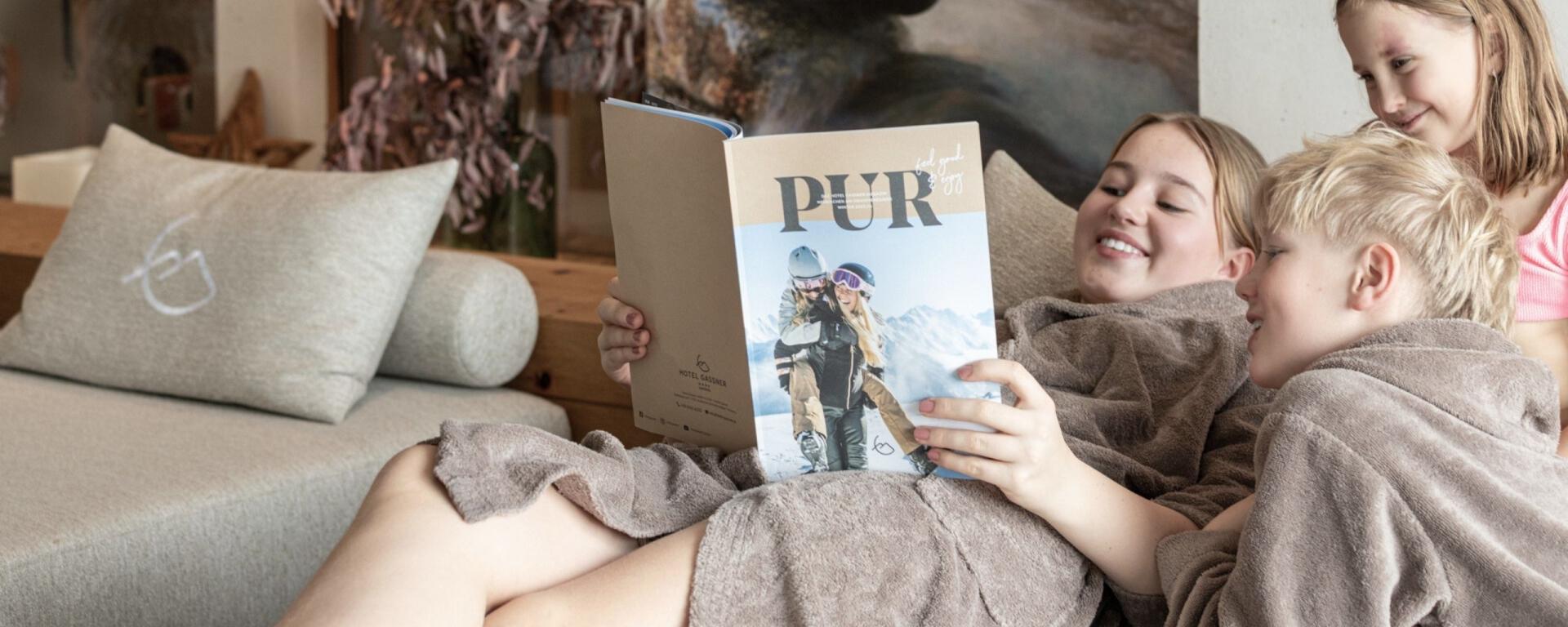 Drei Kinder relaxen im Familienruheraum vom Hotel Gassner und blättern durch das Wintermagazin
