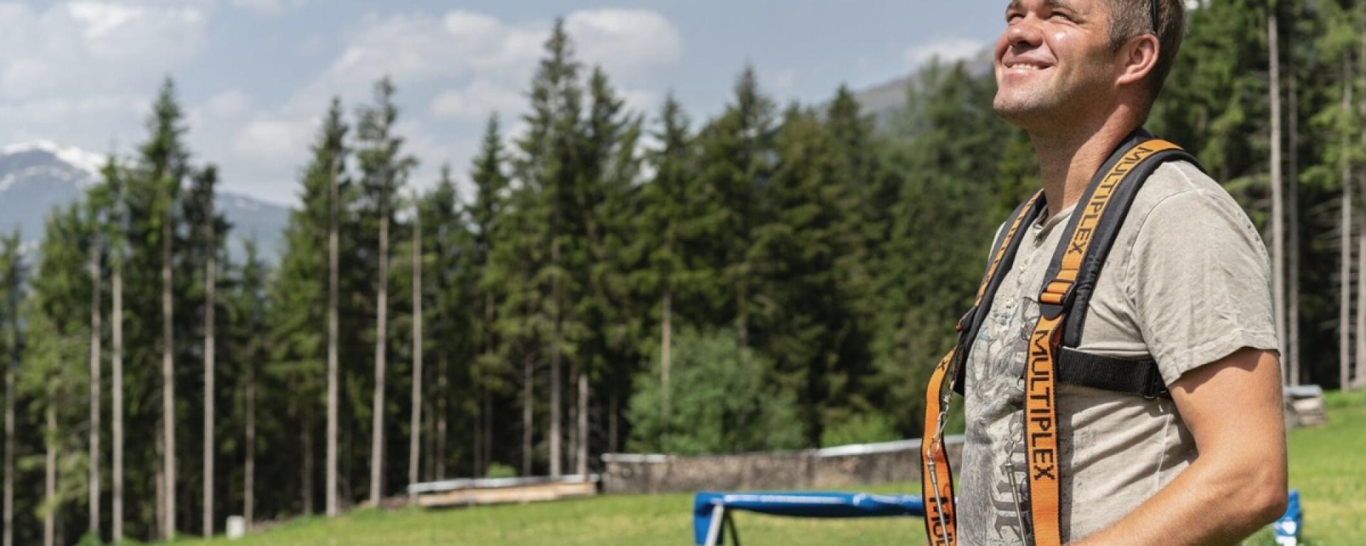 Mann mit Kameragurt im Grünen vor Wald im Hotel Gassner **** Superior