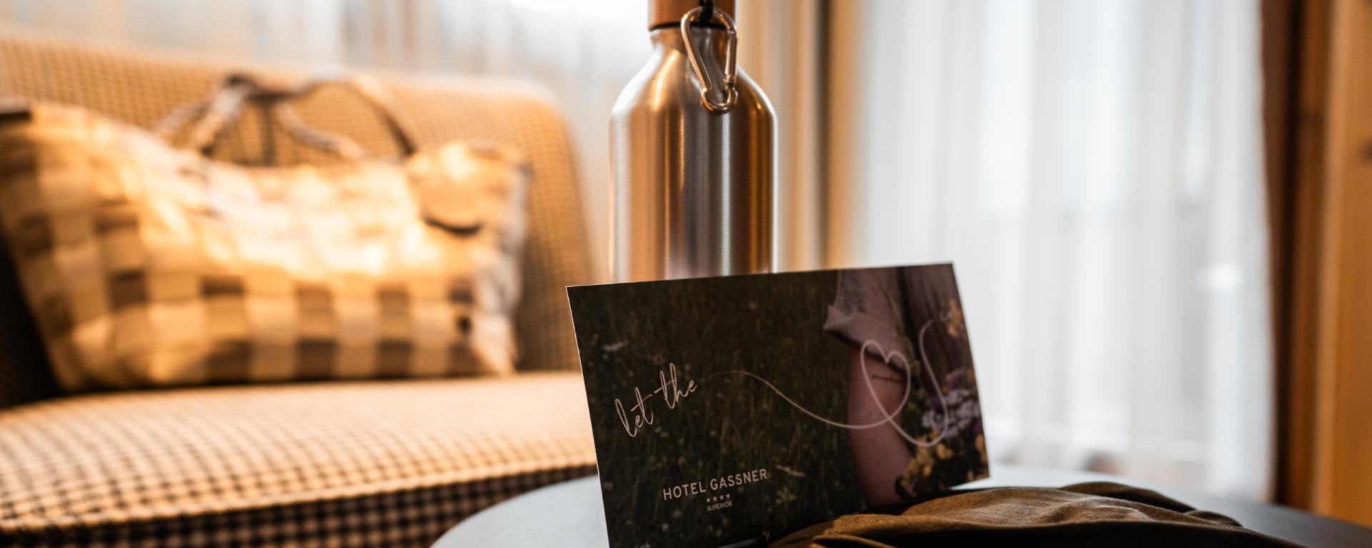 Hotel Gassner **** Superior Tisch mit Wasserflasche und Einladungskarte im gemütlichen Zimmer