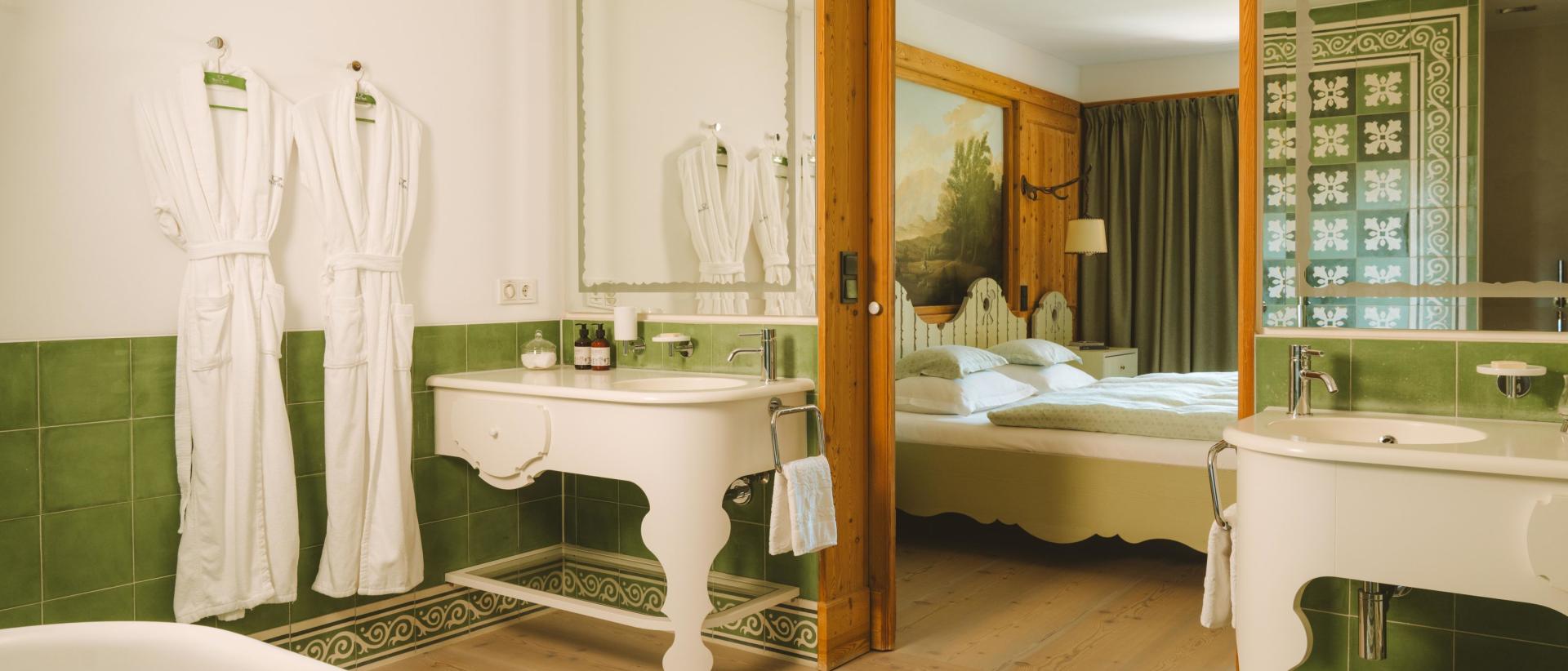 Badezimmer mit Badewanne und Blick ins Schlafzimmer im Hotel Post Lech