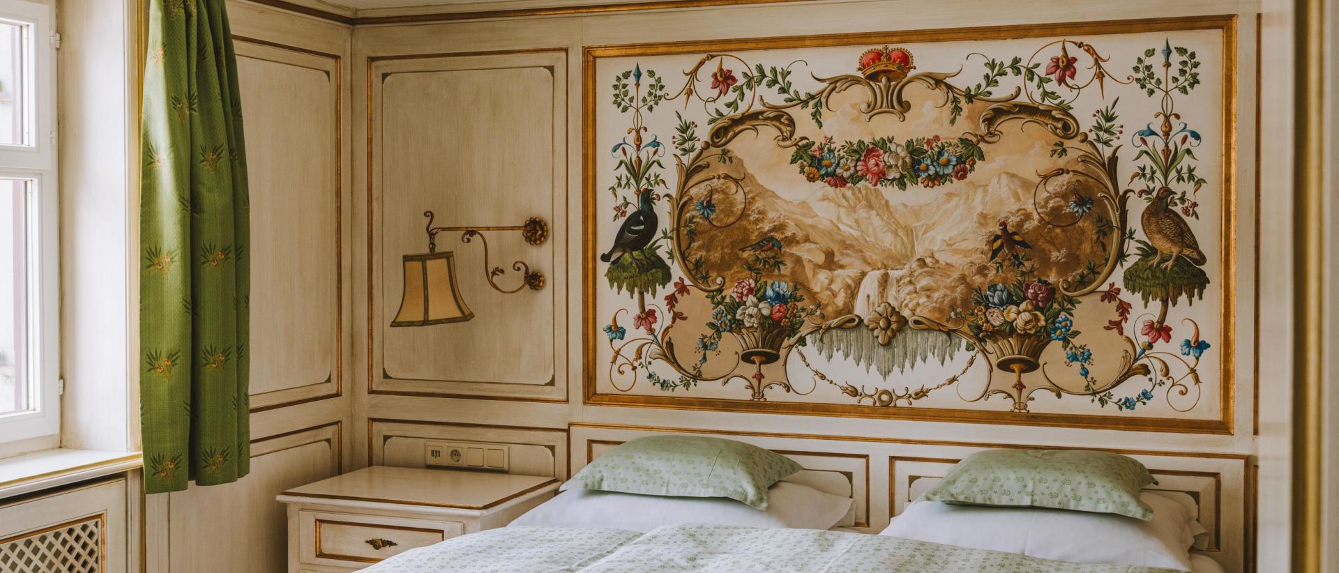 Schlafzimmer im Hotel Post Lech mit Doppelbett und floralem Wandgemälde