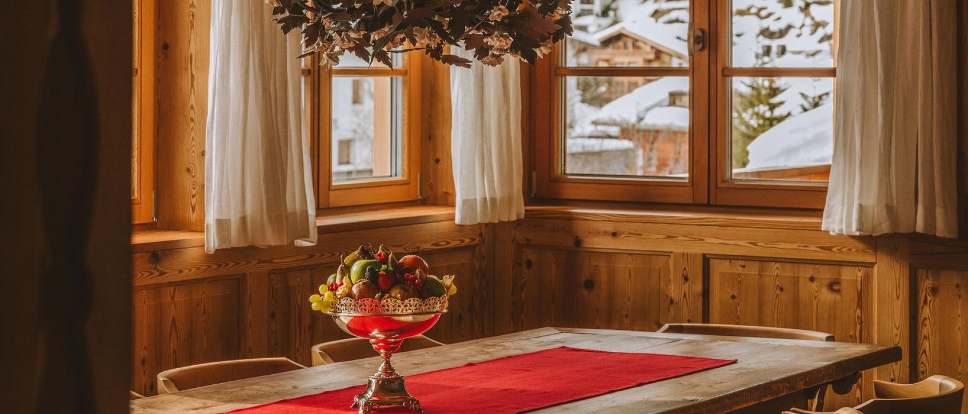 Rustikaler Speisesaal im Hotel Post Lech mit Holztisch und verschneitem Ausblick