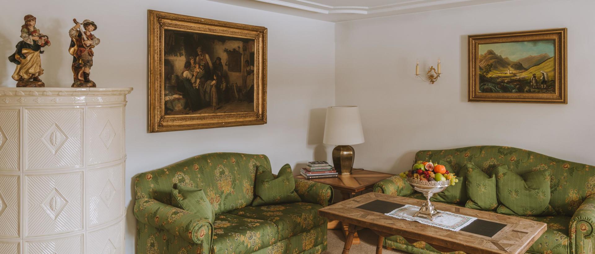Elegante Sitzecke im Hotel Post Lech mit grünen Sofas und Gemälden