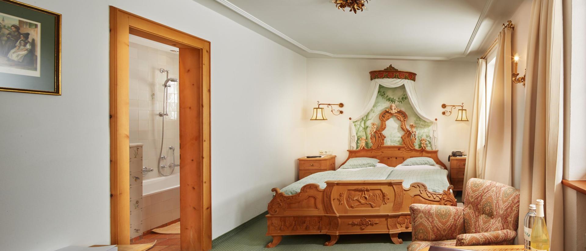 Hotel Post Lech: Traditionelles Doppelzimmer mit verziertem Holzbett und Bad